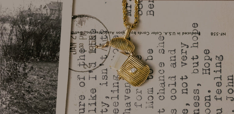A Kinn 14k Gold Diamond Relic Ribbed Locket Necklace laying flat against old photographs and letters