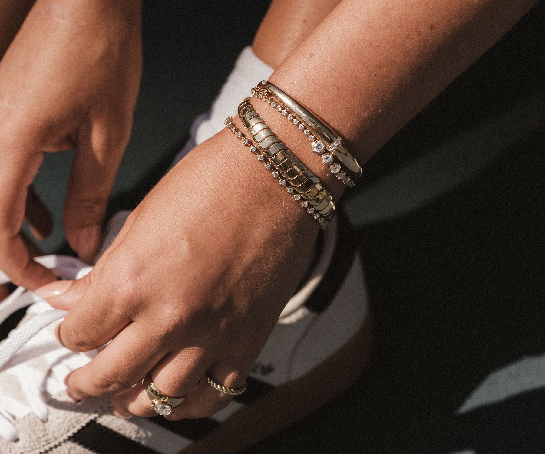 close up of woman's arm wearing Kinn 14k gold and diamond bracelets stacked together