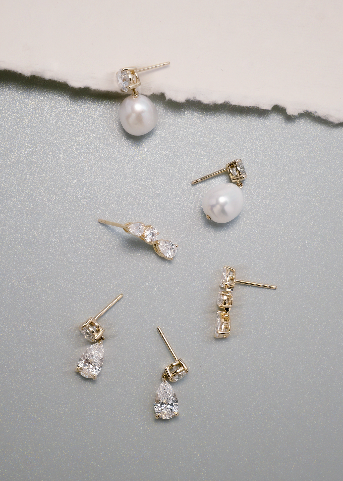 A pair of Kinn 14k Gold Third Time's a Charm Drop Earrings Pear 2.7ctw Diamond laying flat with a Delanie Pearl Drop Earrings and Frankie Pear and Round Diamond Drop Earrings