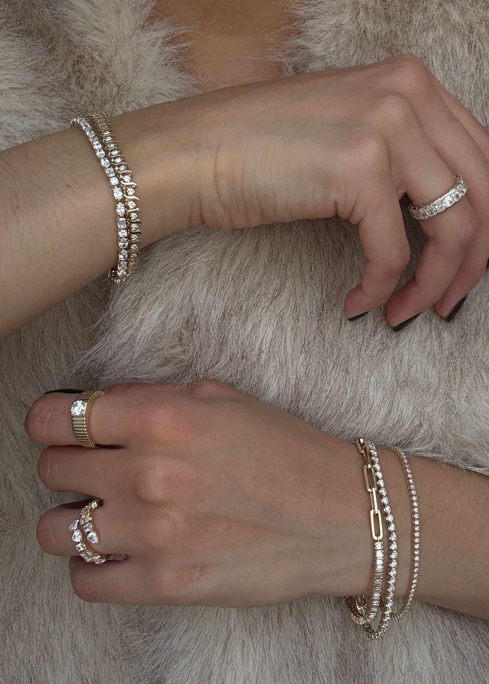 woman in a faux fur top wearing a Kinn 14k Gold Aria Fancy Cut Diamond Wrap Around Ring on her ring finger and a Solis Round Diamond Engagement Ring on her index finger