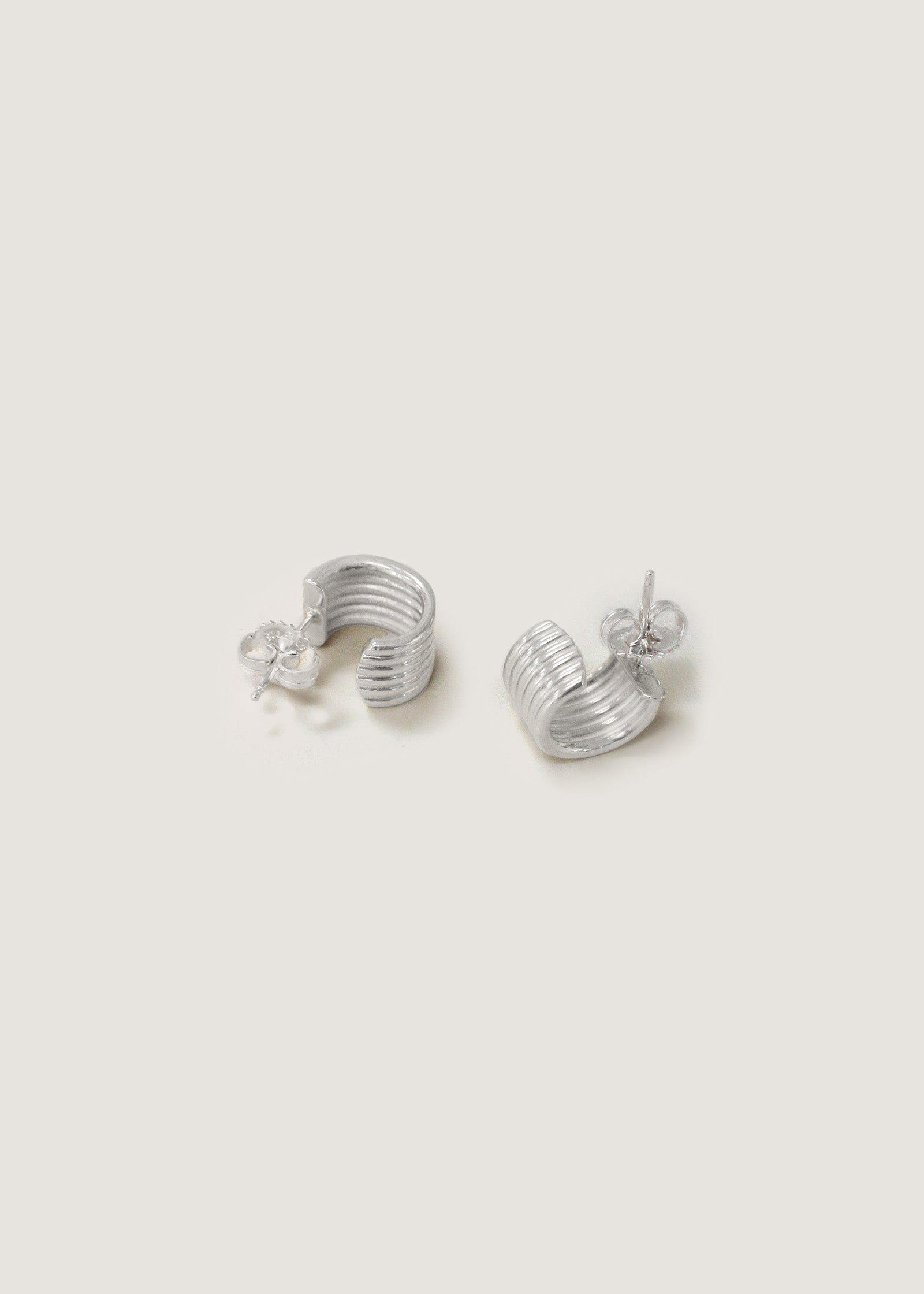 Kinn Studio 925 Sterling Silver Mercer Cuff Hoop Earrings laying on their sides