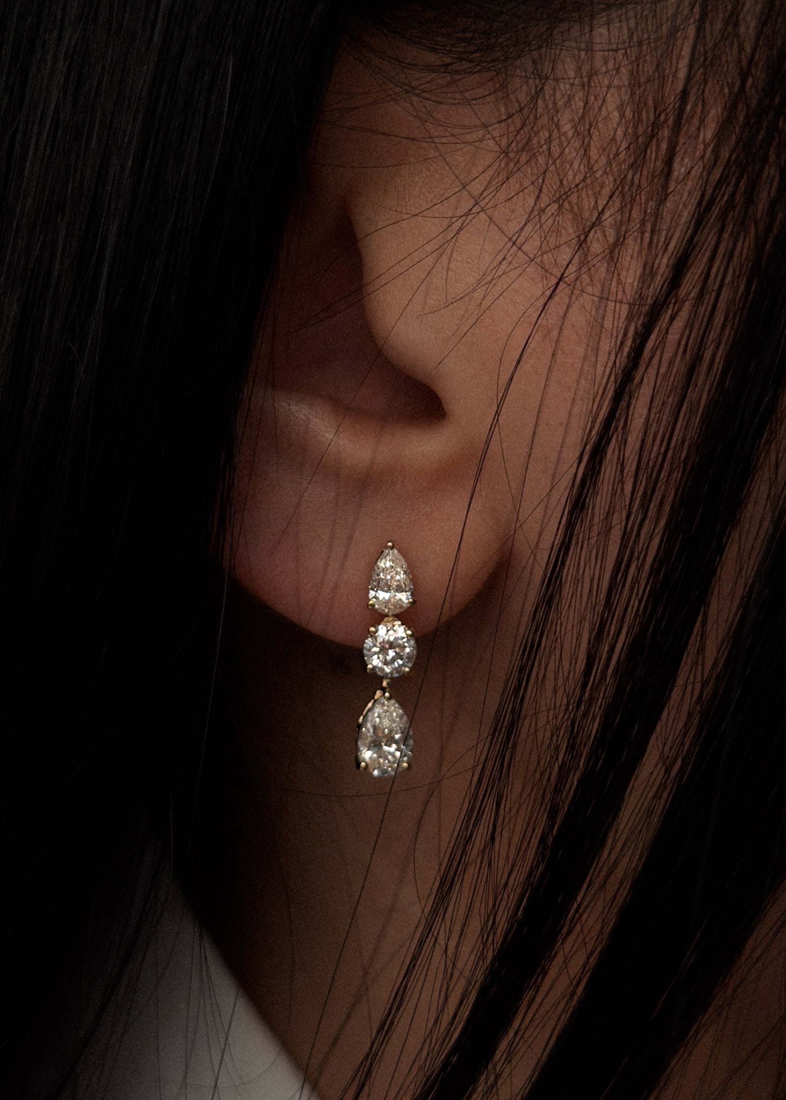 close up of a woman with dark hair wearing a Kinn 14k gold Third Time's a Charm Drop Earrings Pear 2.7ctw Diamond