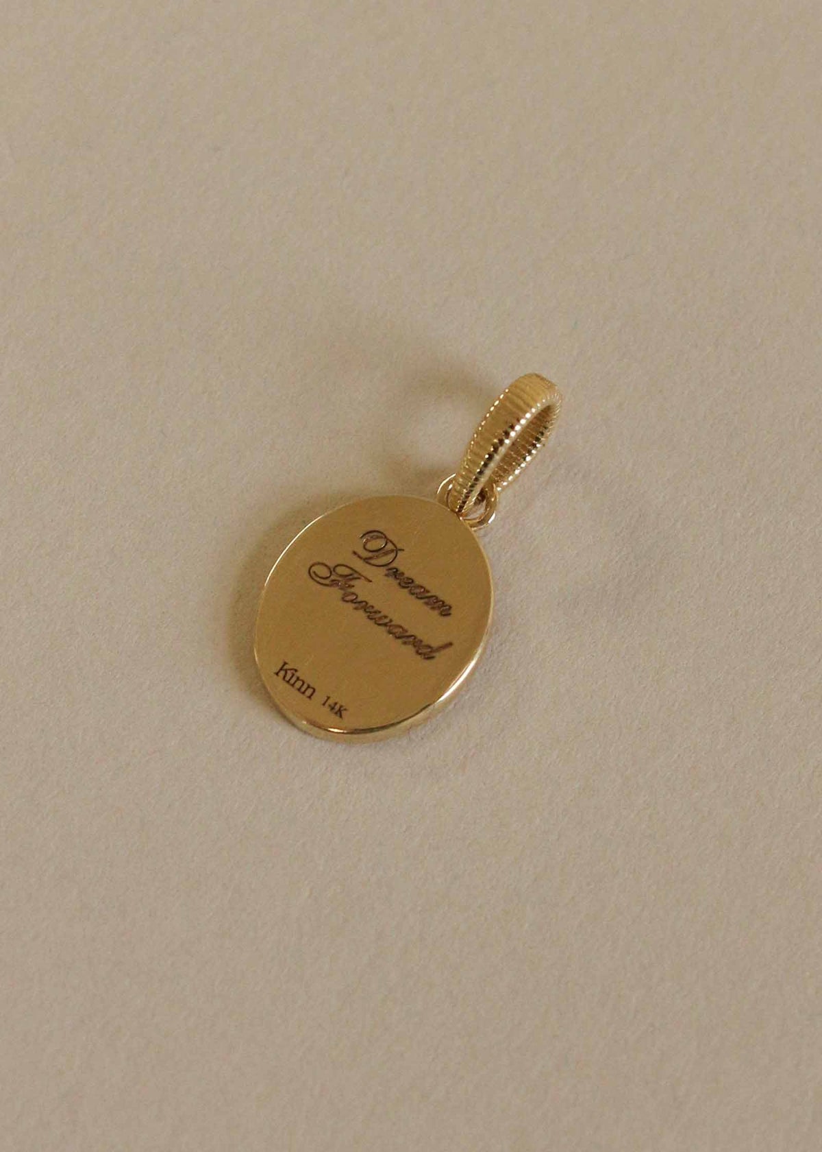 Back of the Kinn 14k Gold Butterfly Dream Diamond Pendant engraved with "Dream Forward" laying flat