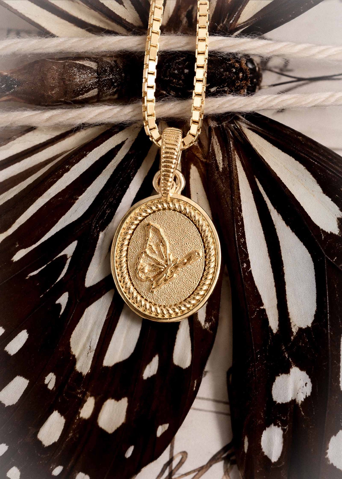 A Kinn 14k Gold Butterfly Dream Pendant on a box chain against a butterfly background