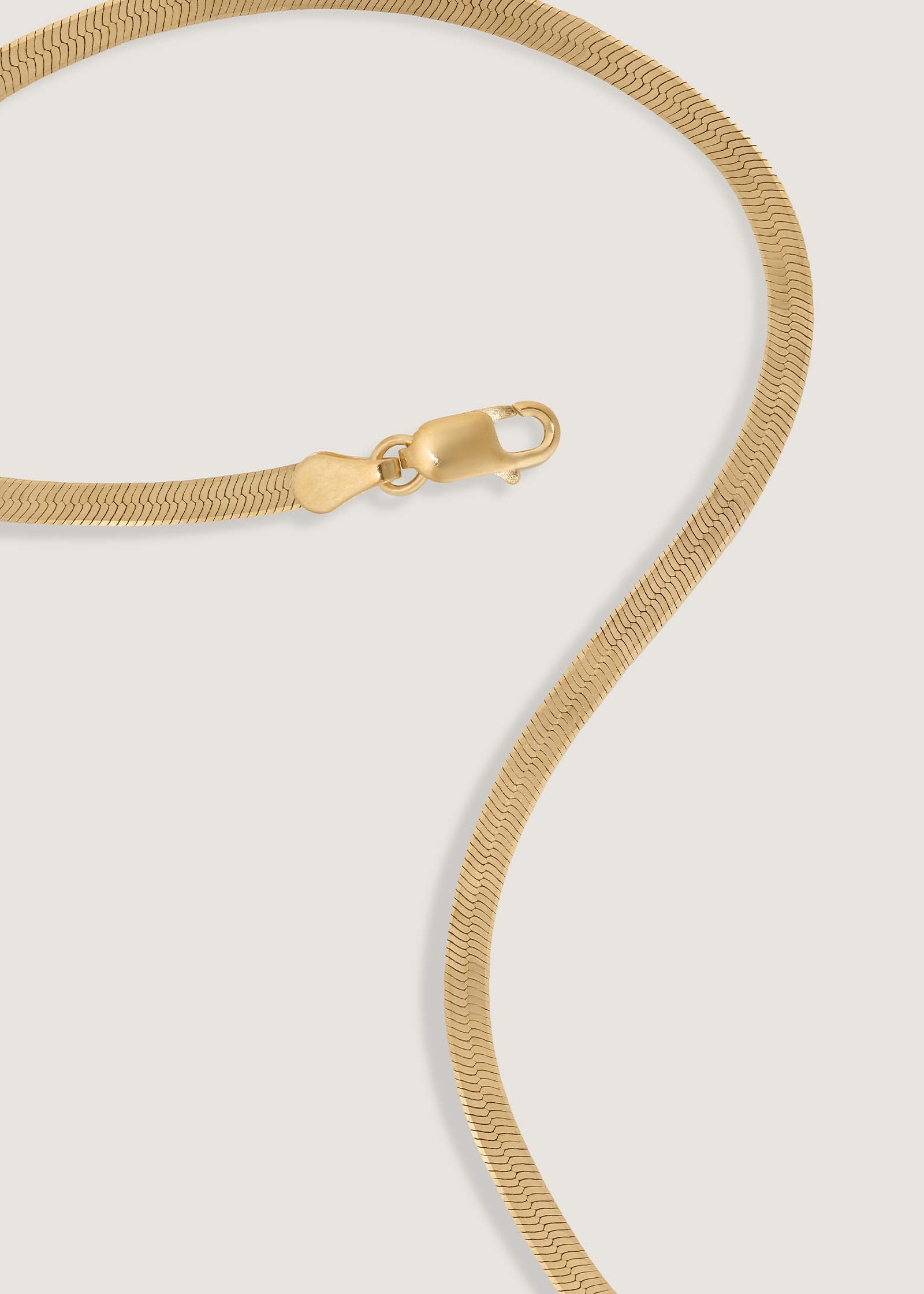 A Kinn 14k Gold Carter Herringbone Chain Necklace laying flat showing the lobster clasp closure