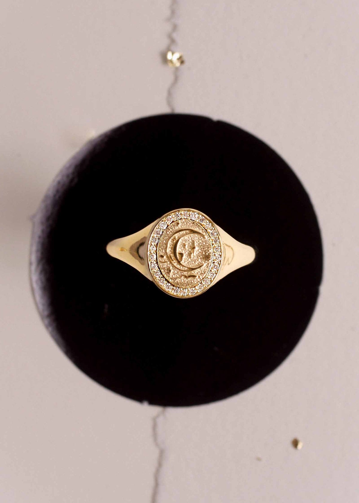 A Kinn 14k Gold Crescent Dream Diamond Signet Ring sitting on a velvet stand