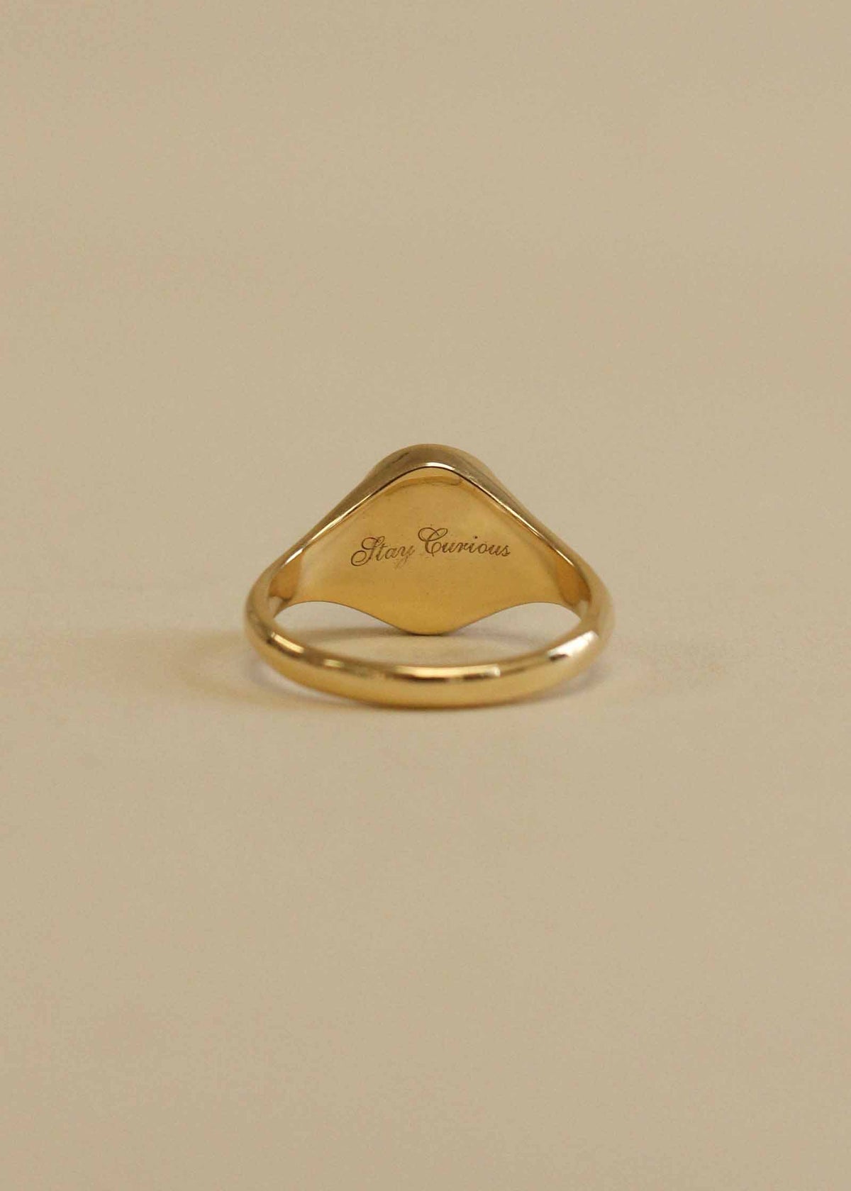A Kinn 14k Gold Crescent Dream Diamond Signet Ring showing the back of the signet engraved with "Stay Curious" in script font