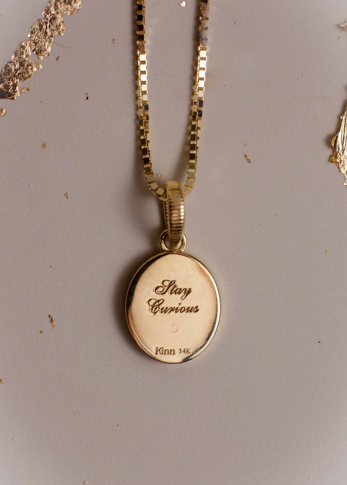 Back of a Kinn 14k Gold Crescent Dream Diamond Pendant engraved with "Stay Curious"