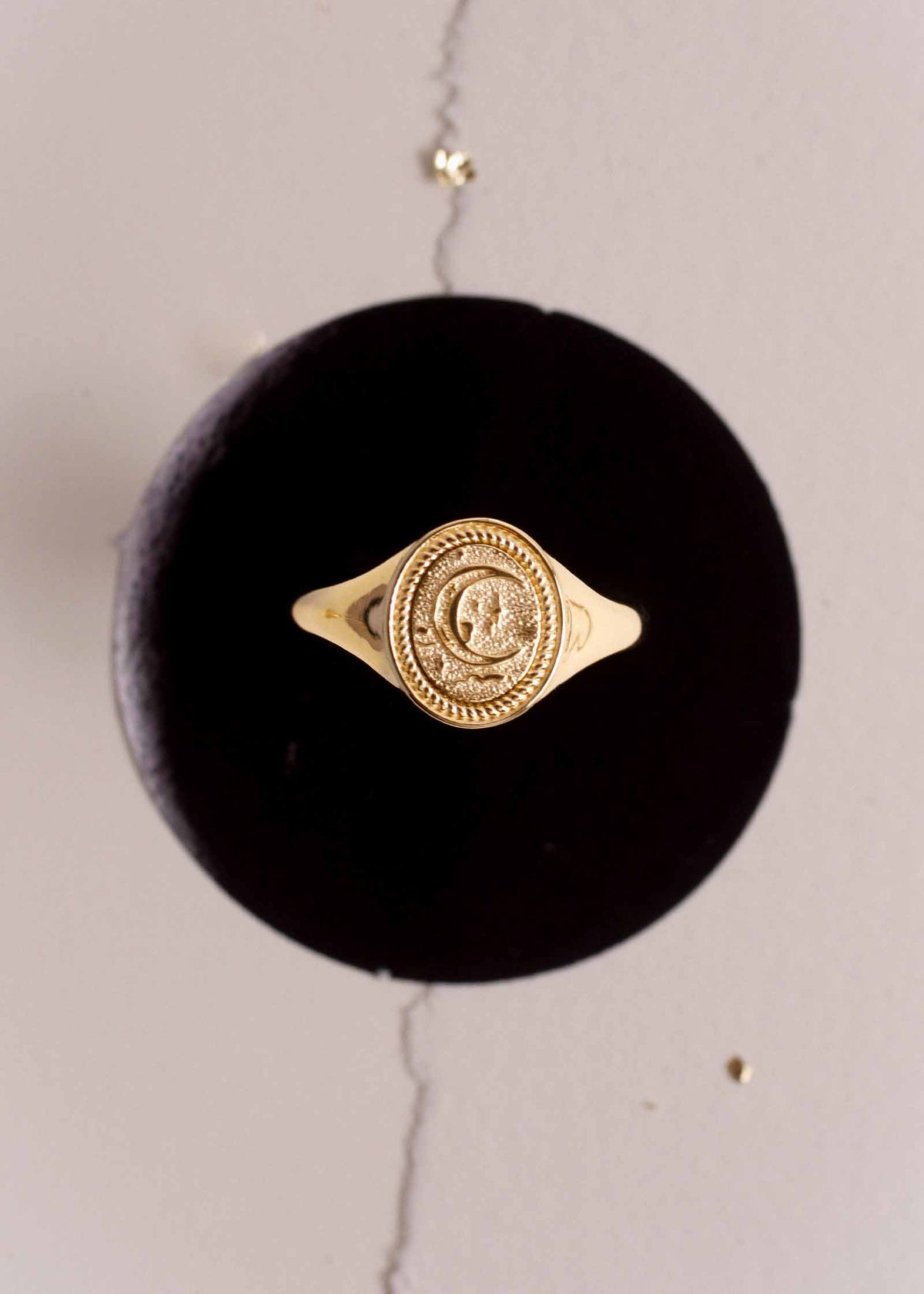 a Kinn 14k Gold Crescent Dream Signet Ring sitting up on a velvet stand