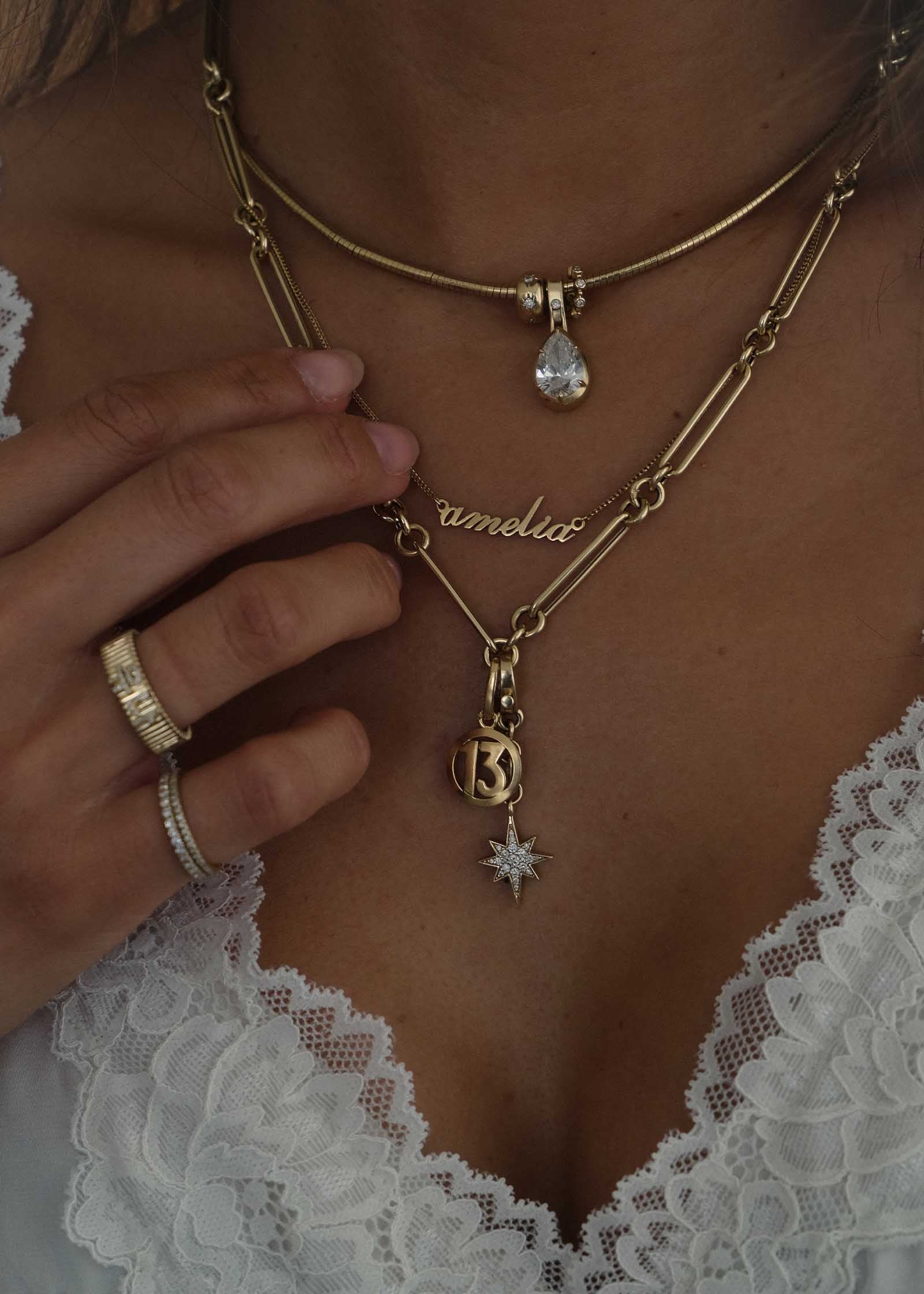 Jennie wearing a Kinn 14k Gold Dear Kaia Nameplate Necklace in English reading amelia layered with other necklaces