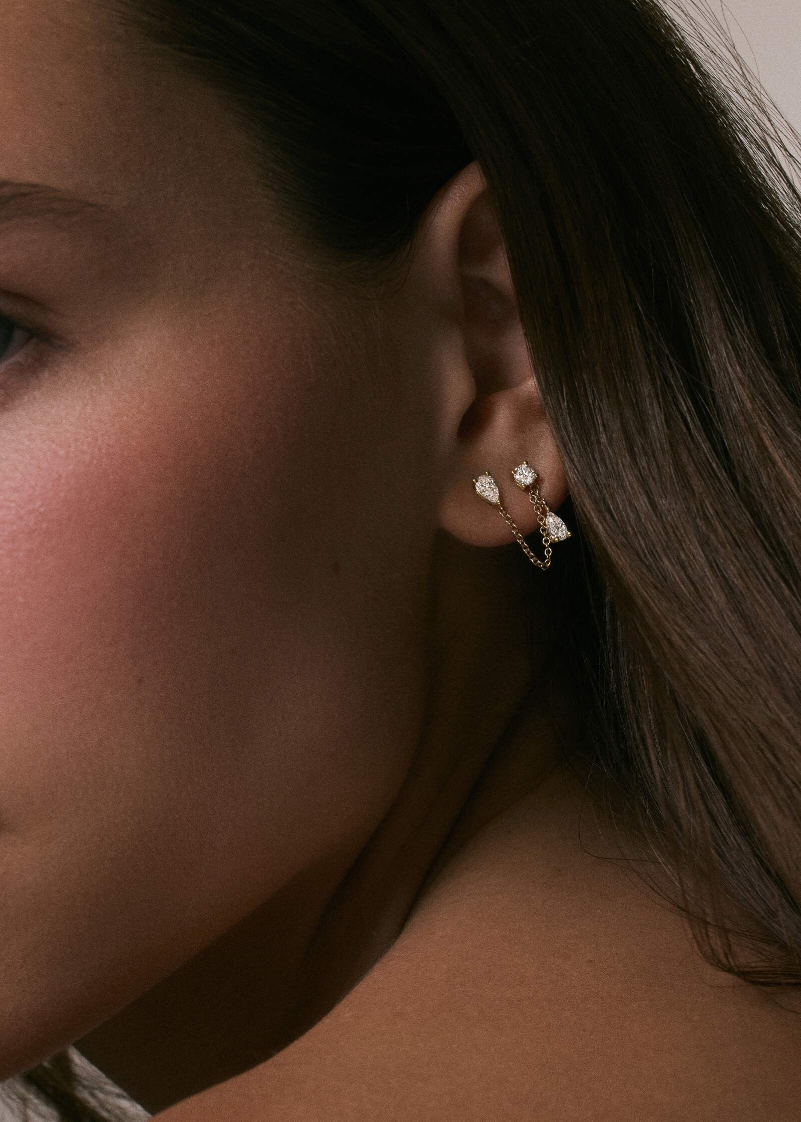 A close up of a woman wearing a Kinn x Prince 14k Gold Doubles Diamond Chain Earring