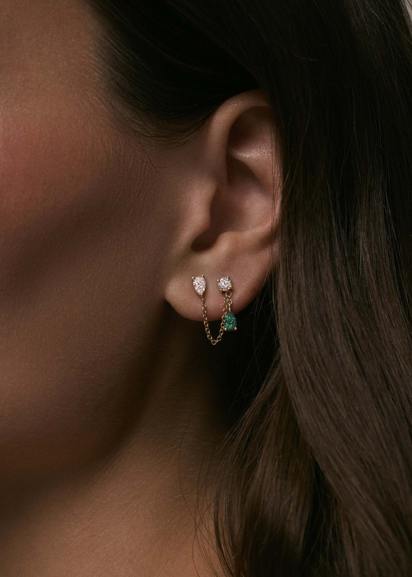 close up of a woman's ear wearing a Kinn x Prince 14k Gold Doubles Diamond & Emerald Chain Earring