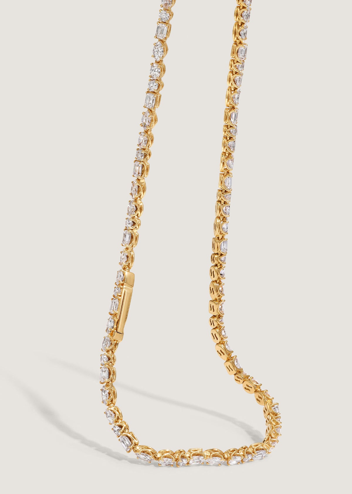 A close up of a Kinn 14k Yellow Gold Esme Fancy Shape Diamond Tennis Necklace draped down showing the clasp