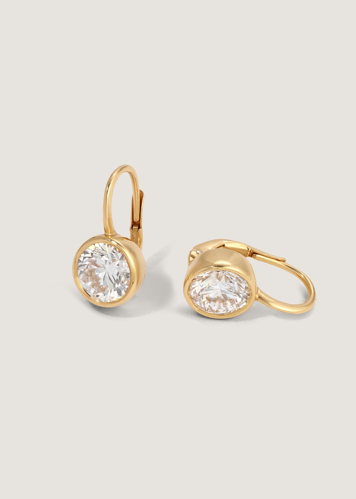 A pair of Kinn 14k Yellow Gold Harper 4ctw Round Drop Earrings with one earring laid sideways