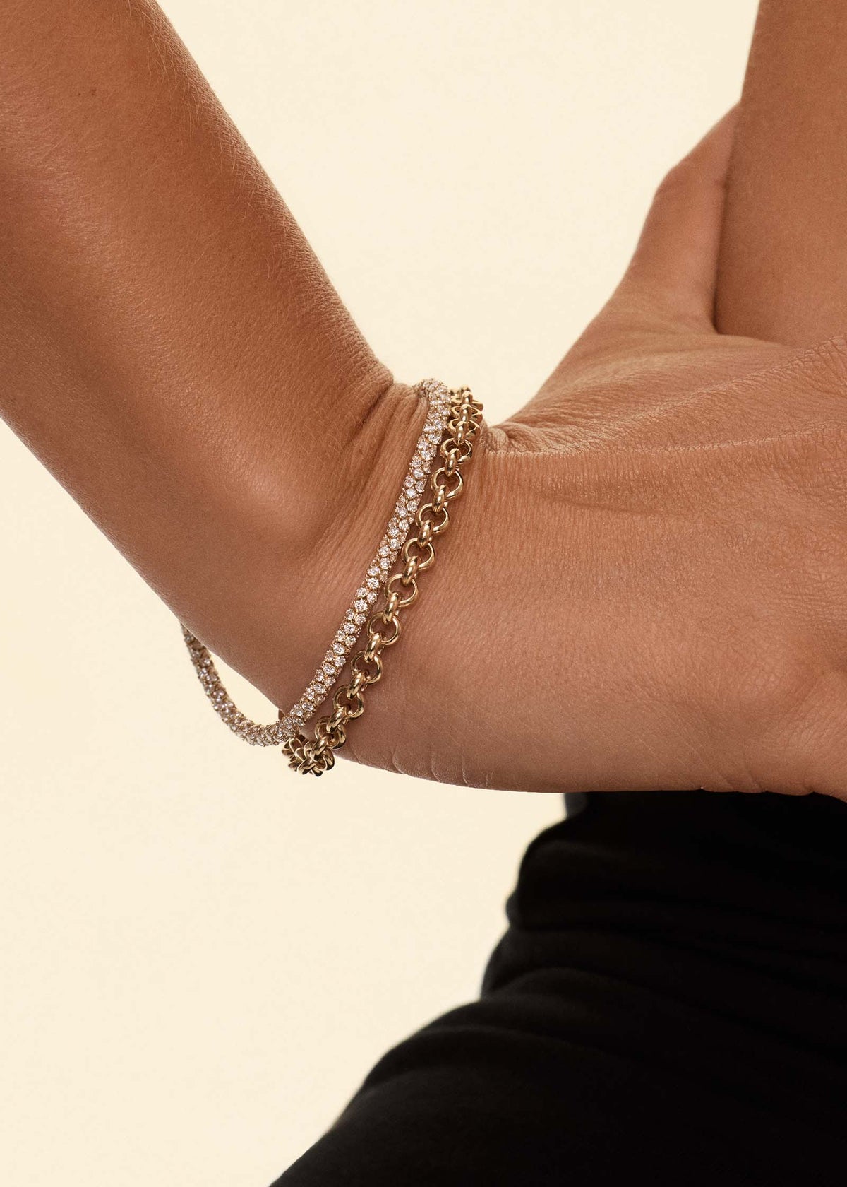 A woman with her hands on her hip wearing a Kinn 14k Gold Isadora Tubular Diamond Tennis Bracelet stacked with a Matis Rolo Chain Bracelet