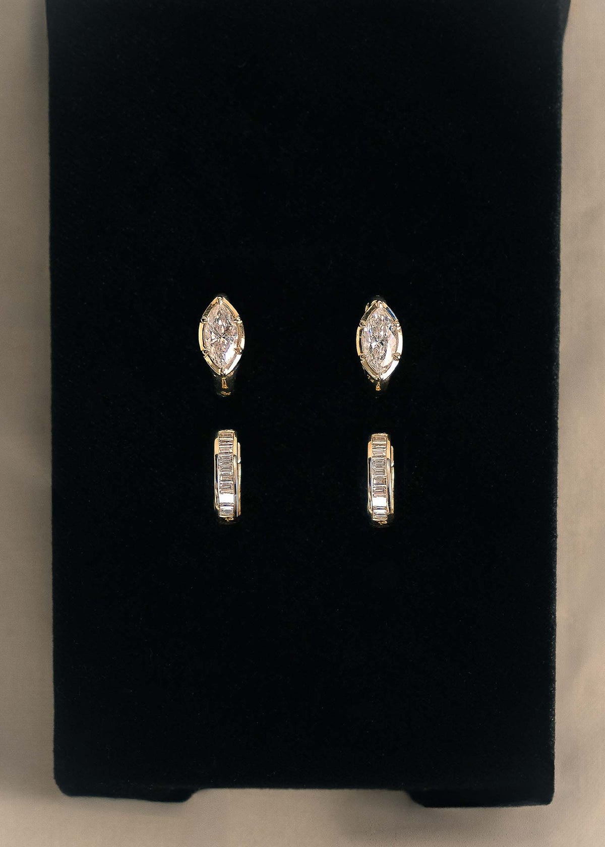 A pair of Kinn 14k Gold Jackson Marquise Diamond Huggie Hoop Earrings  and Bobbi Baguette Diamond Huggie Earrings sitting upright