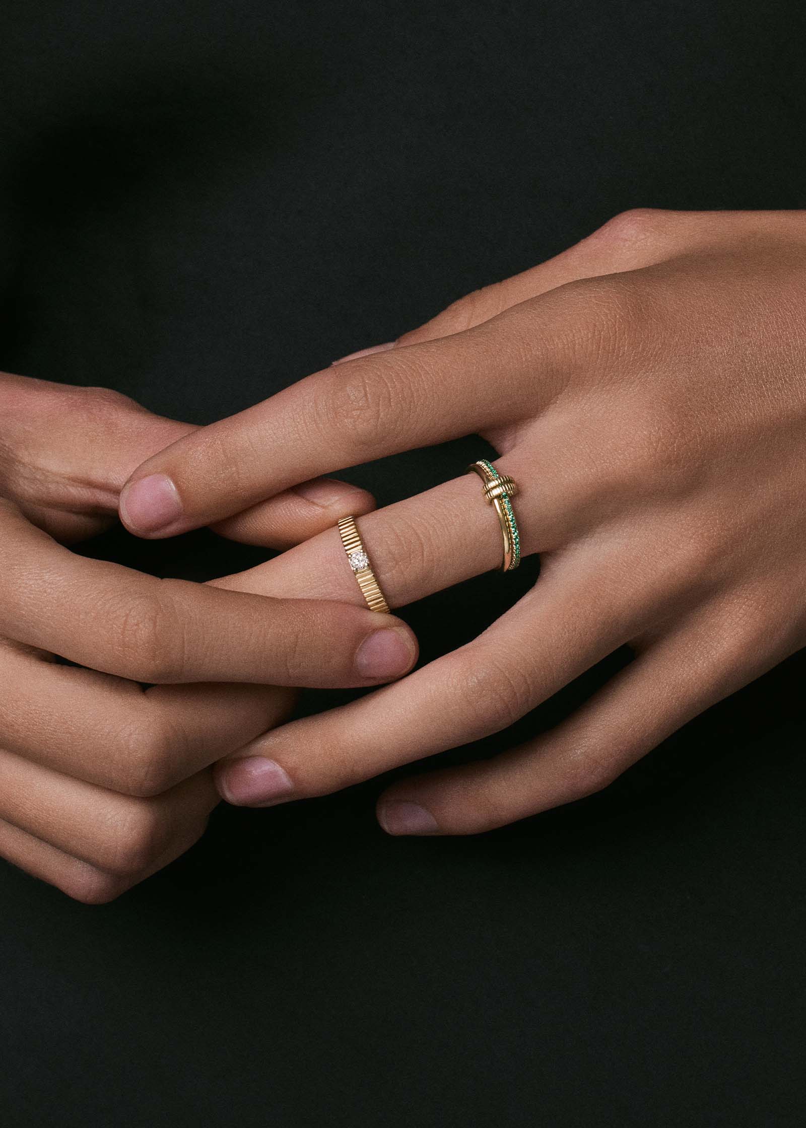 close up of a woman's hand wearing a Kinn x Prince 14k Gold Lesley Linked Emerald Band Ring stacked with a Petite Solis Ribbed Diamond Ring