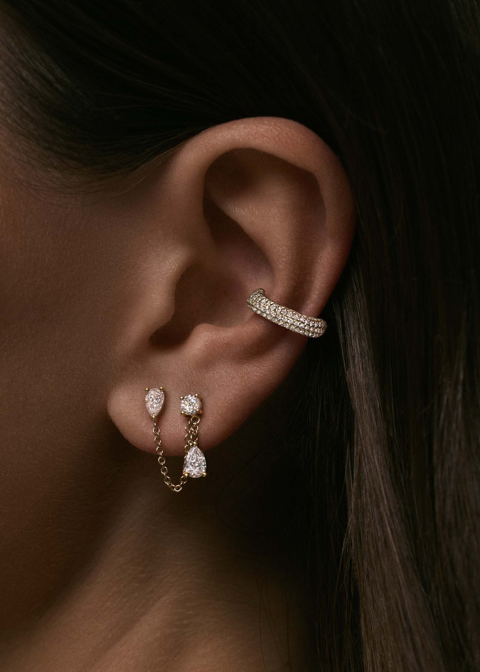A close up of an ear wearing a 14k Gold Love Pavé Diamond Earring Cuff layered with a Doubles Diamond Chain Earring
