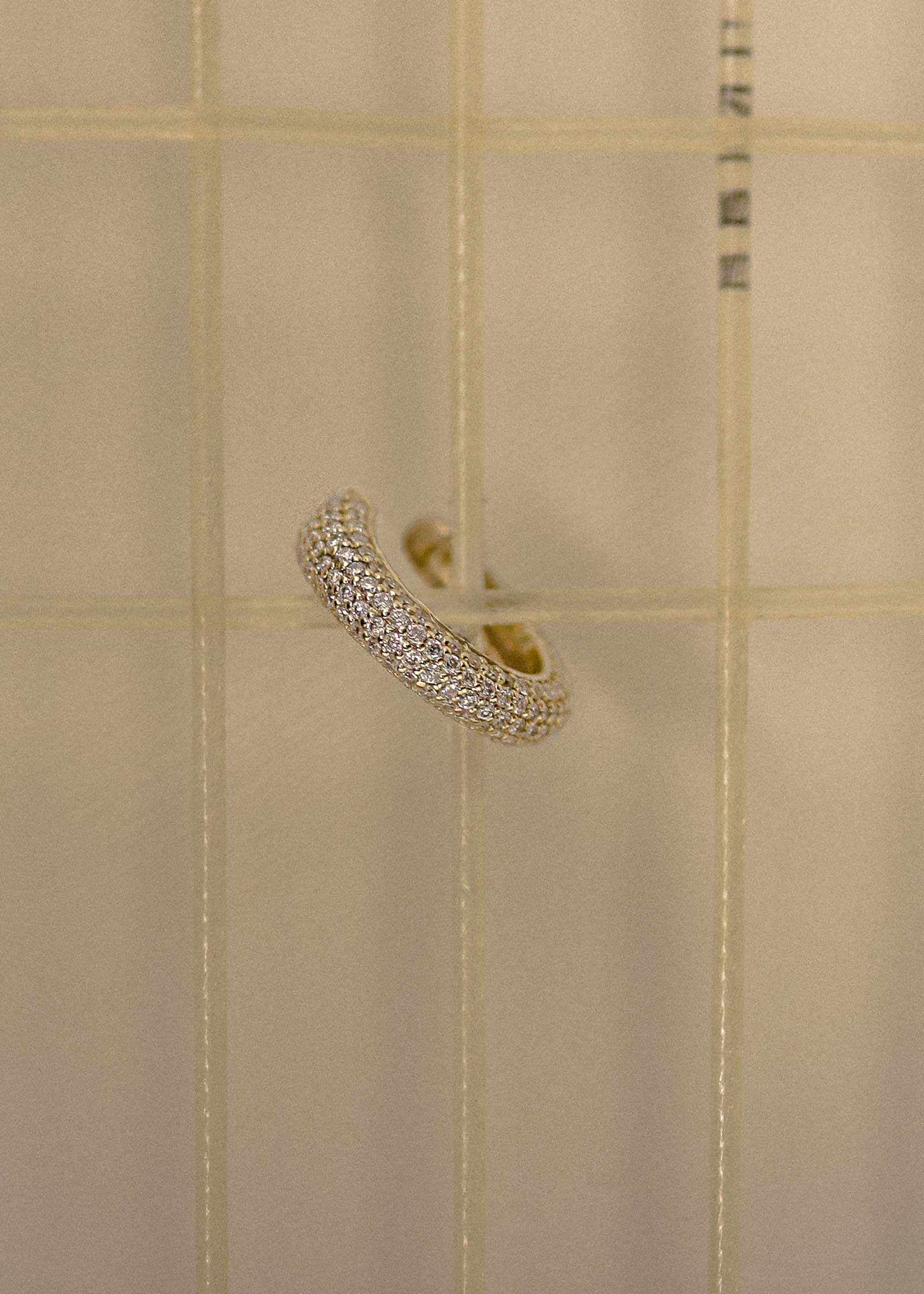 A 14k Gold Love Pavé Diamond Earring Cuff hooked onto the strings of a vintage Prince tennis racquet