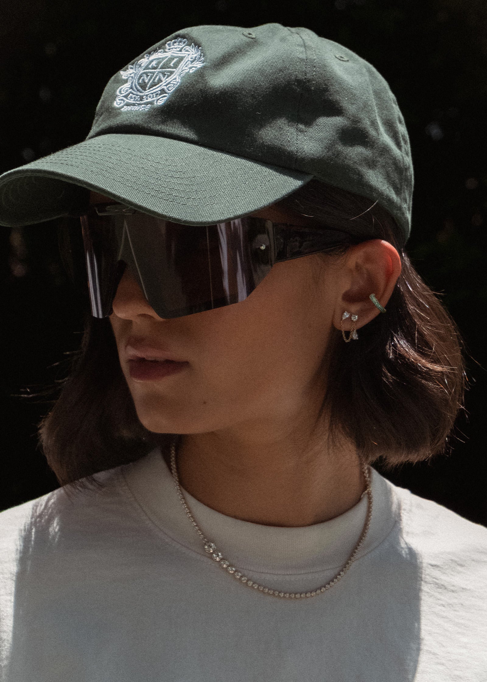 woman in a Club Cap and Naomi Tennis Necklace wearing a Kinn x Prince 14k Gold Love Pavé Emerald Earring Cuff layered with a Doubles Diamond Chain Earring