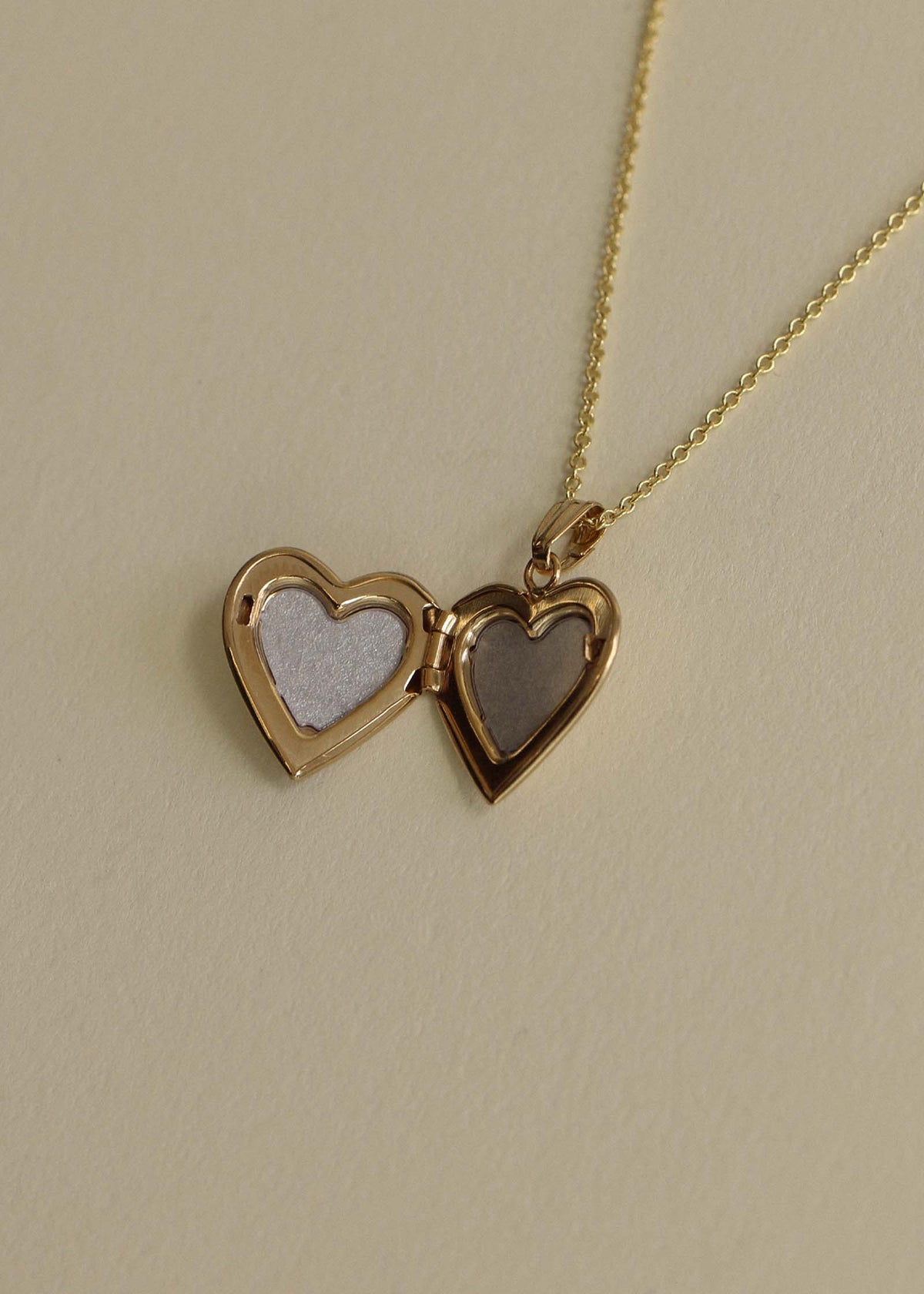 Interior of a Kinn 14k Gold Maison Heart Locket Necklace laying flat