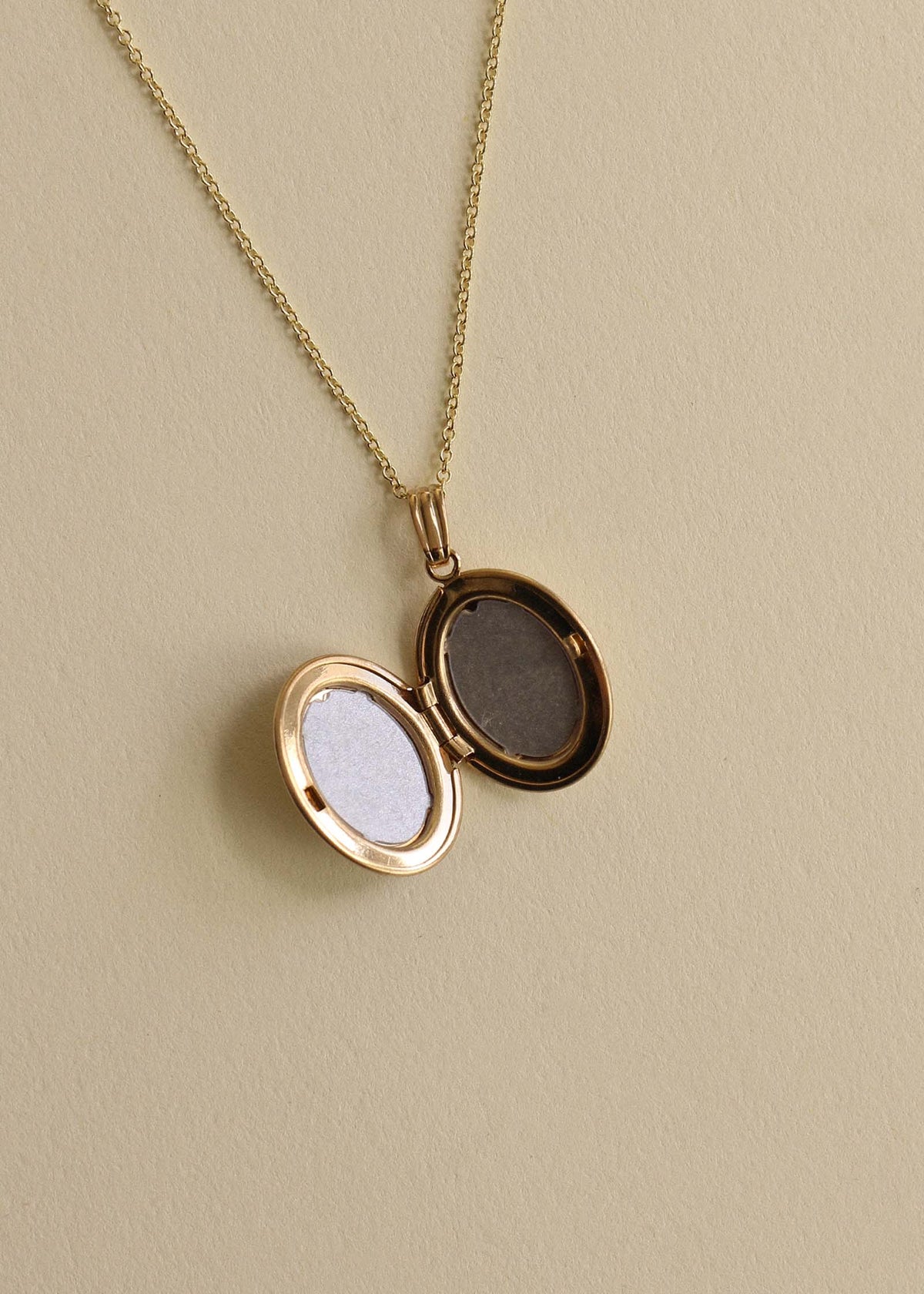 Interior of a Kinn 14k Gold Maison Oval Locket Necklace laying flat