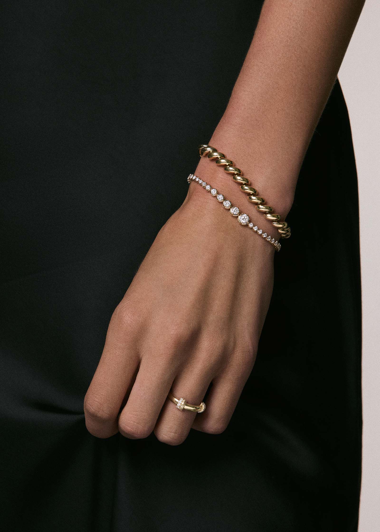 woman's arm wearing a Kinn x Prince 14k Gold Naomi Graduated Diamond Tennis Bracelet stacked with a Hampshire House Bracelet on her wrist and wearing a Rally Pavé Diamond Ring on her ring finger