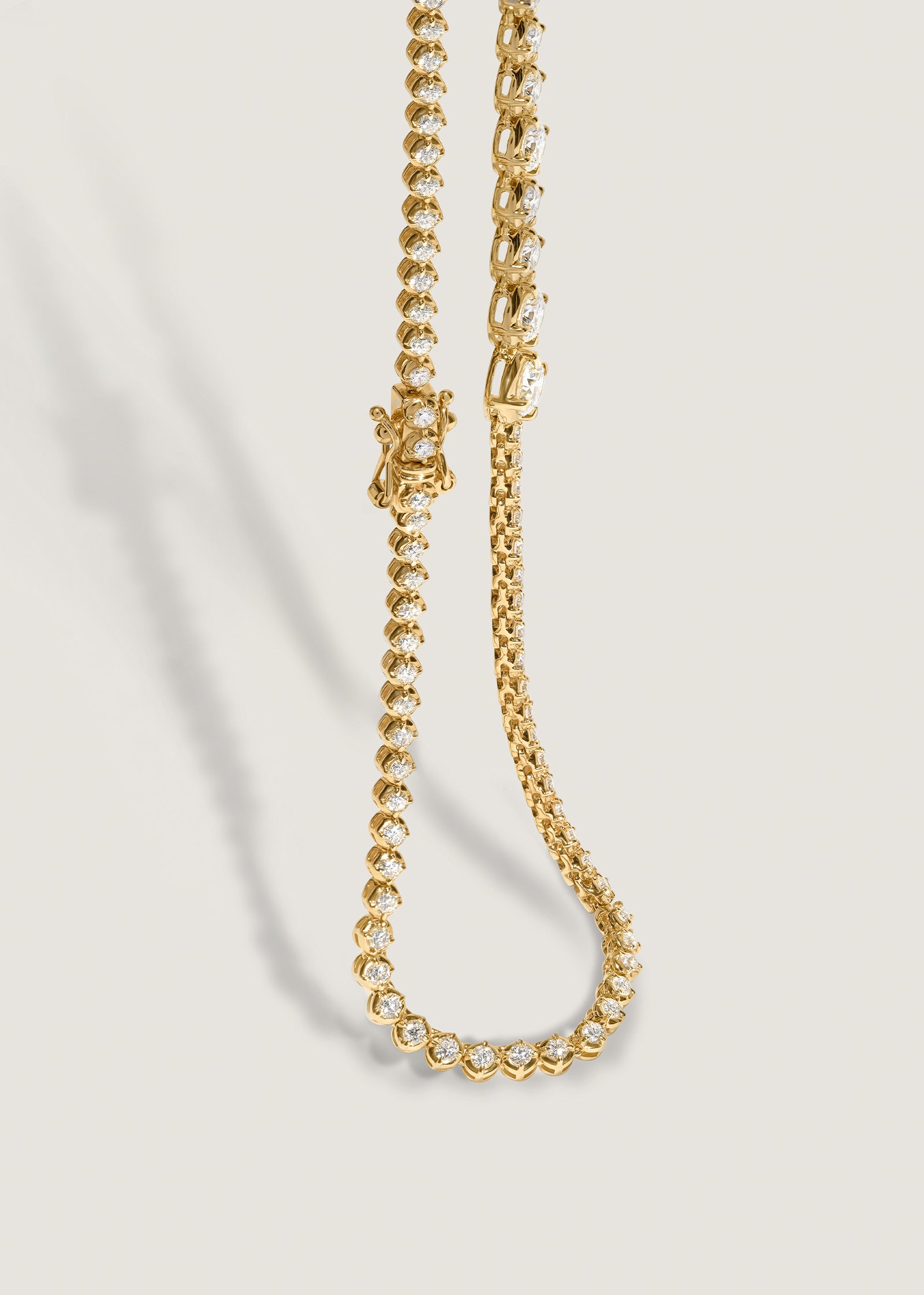 A Kinn x Prince 14k Gold Naomi Graduated Diamond Tennis Necklace draped down at an angle showing the safety box clasp