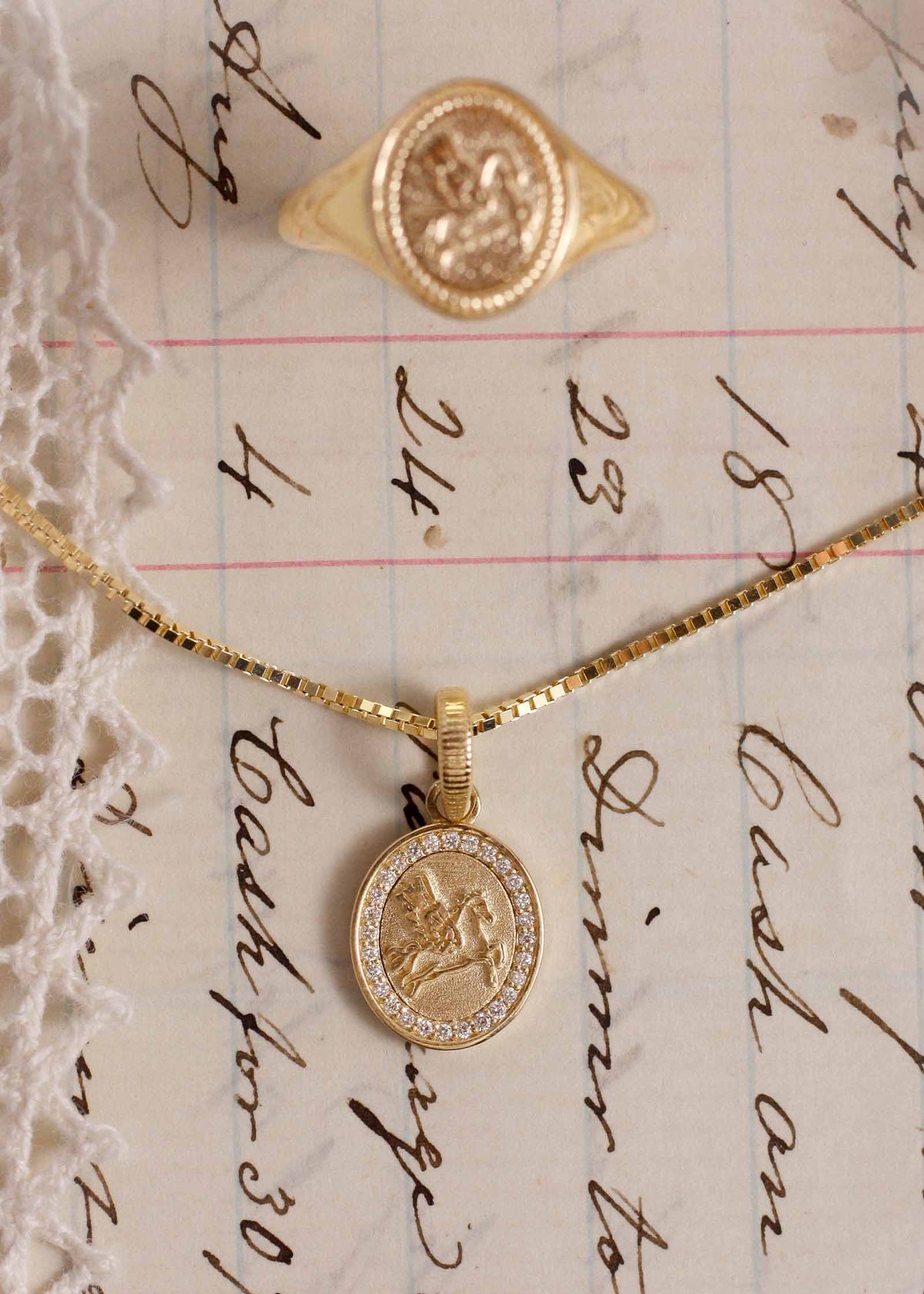A Kinn 14k Gold Pegasus Dream Diamond Pendant on a box chain laying flat