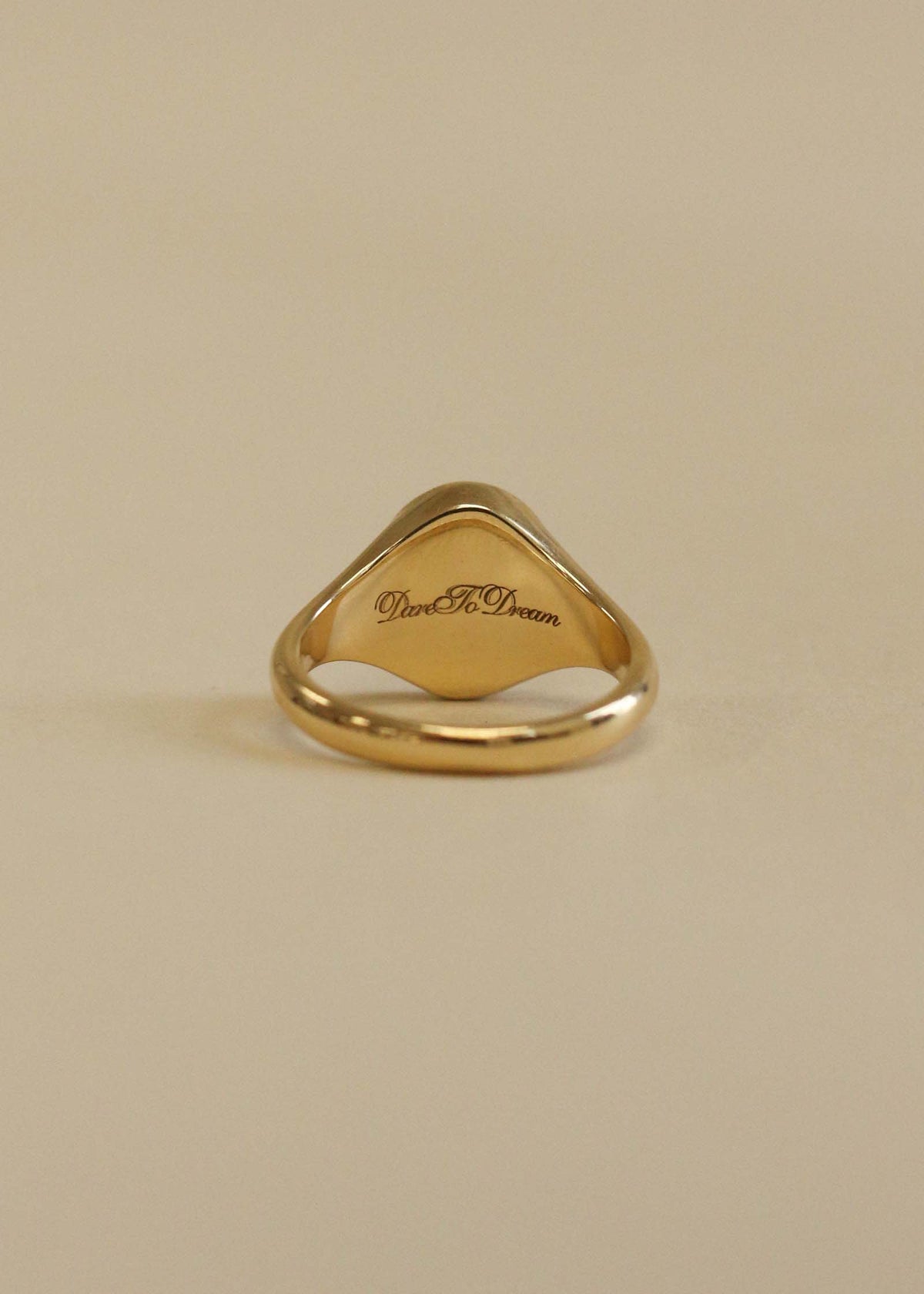 A Kinn 14k Gold Pegasus Dream Diamond Signet Ring showing the back of the signet engraved with "Dare To Dream" in script font