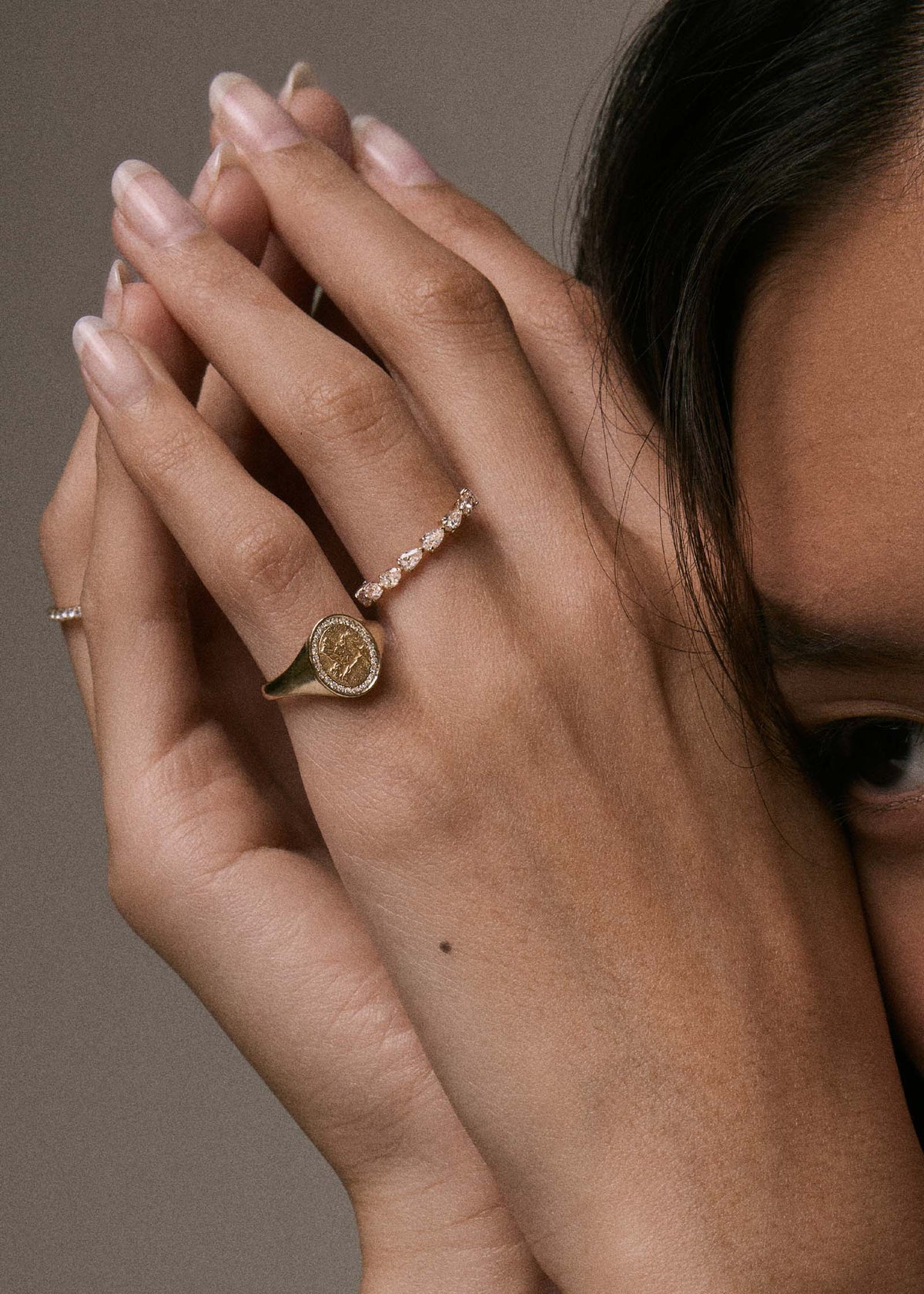 close up of a model resting her head against her hands wearing a Kinn 14k Gold Pegasus Dream Diamond Signet Ring on her pinky finger