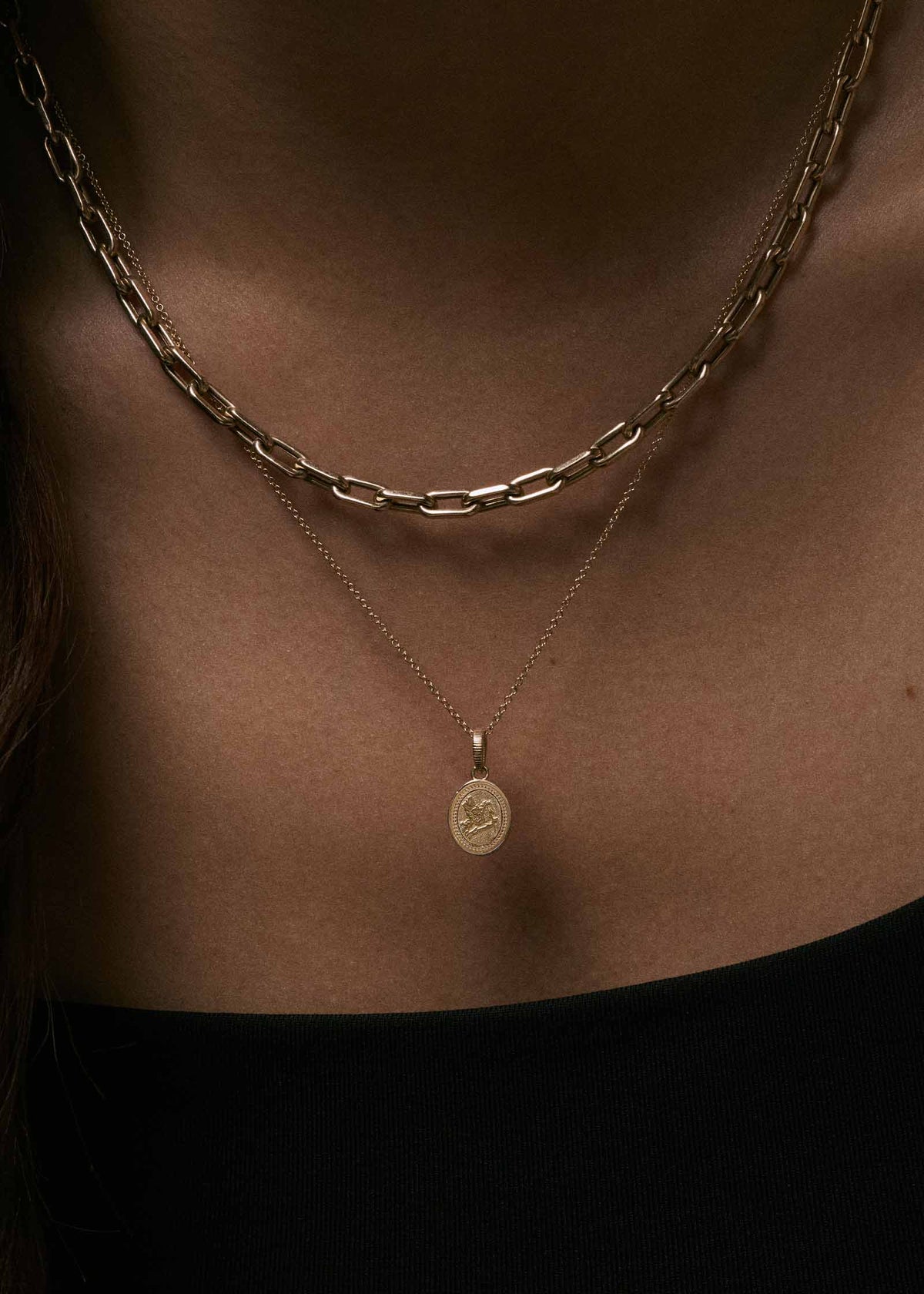 A close up of a woman wearing a Kinn 14k Gold Pegasus Dream Pendant on a micro rolo chain necklace