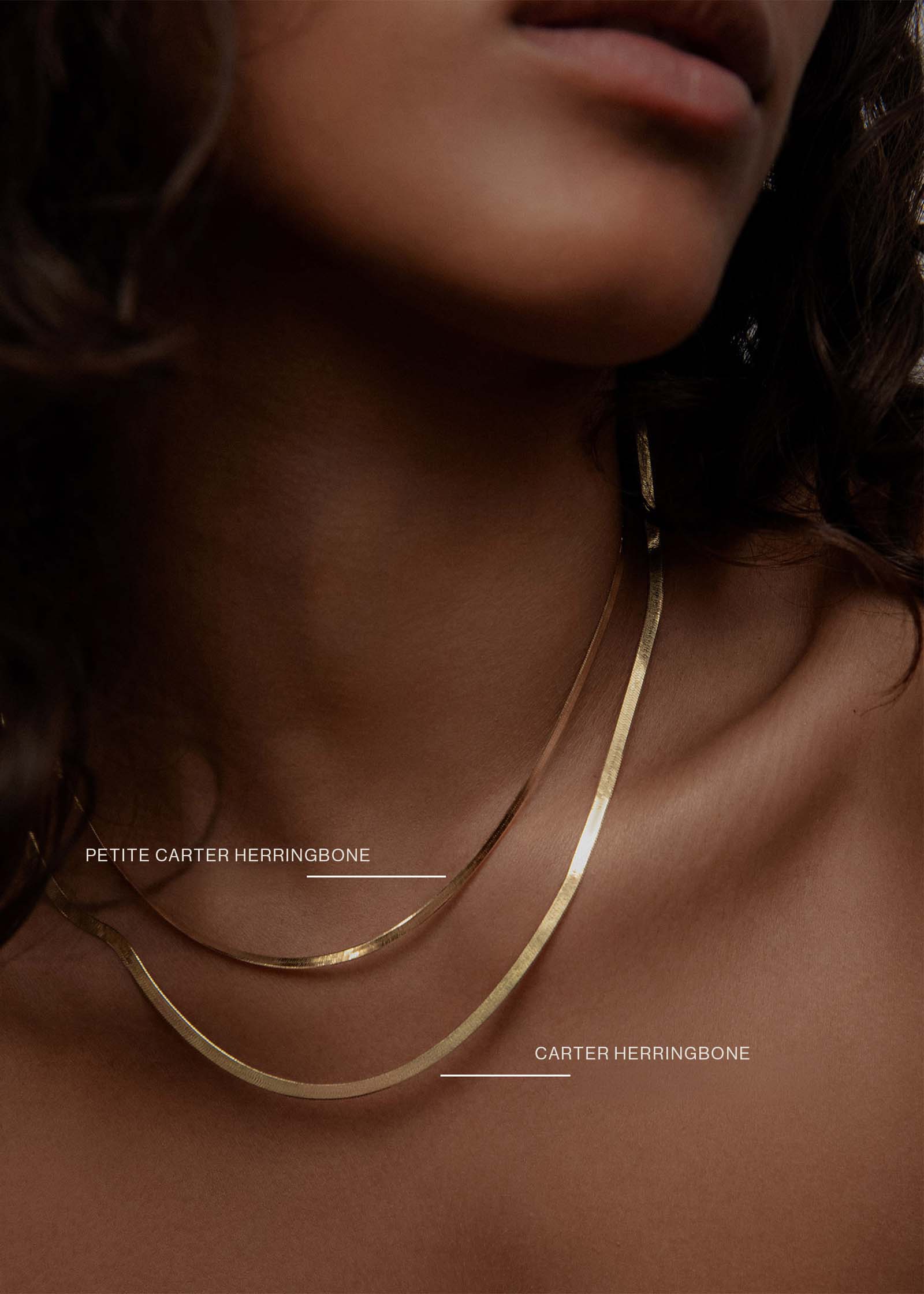 A woman wearing a Kinn 14k Gold Carter Herringbone Chain Necklace and Petite Carter Herringbone Chain layered together as a size comparison