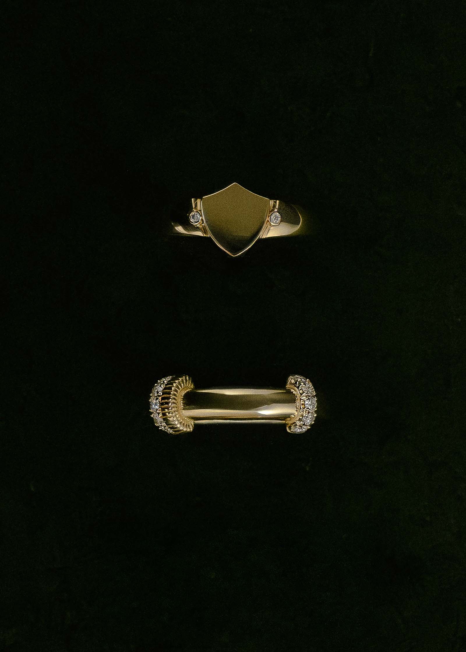 A Kinn x Prince 14k Ace Shield Diamond Signet Ring and 14k Gold Rally Pavé Diamond Ring against a black background