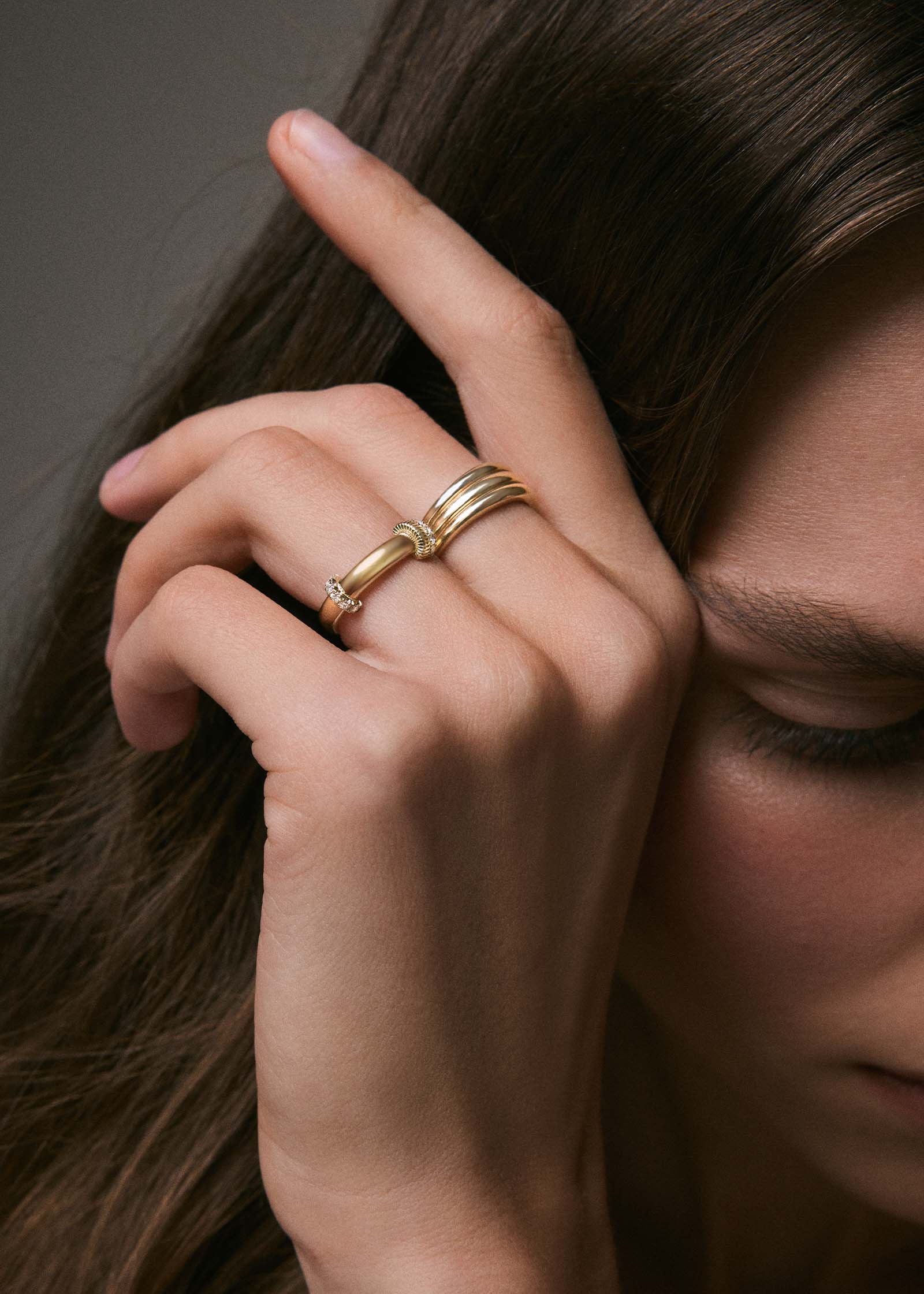close up of a woman's hand resting against her head wearing a Kinn x Prince 14k Gold Rally Pavé Diamond Ring on her ring finger and a Francoise Ellipse Ring on her middle finger