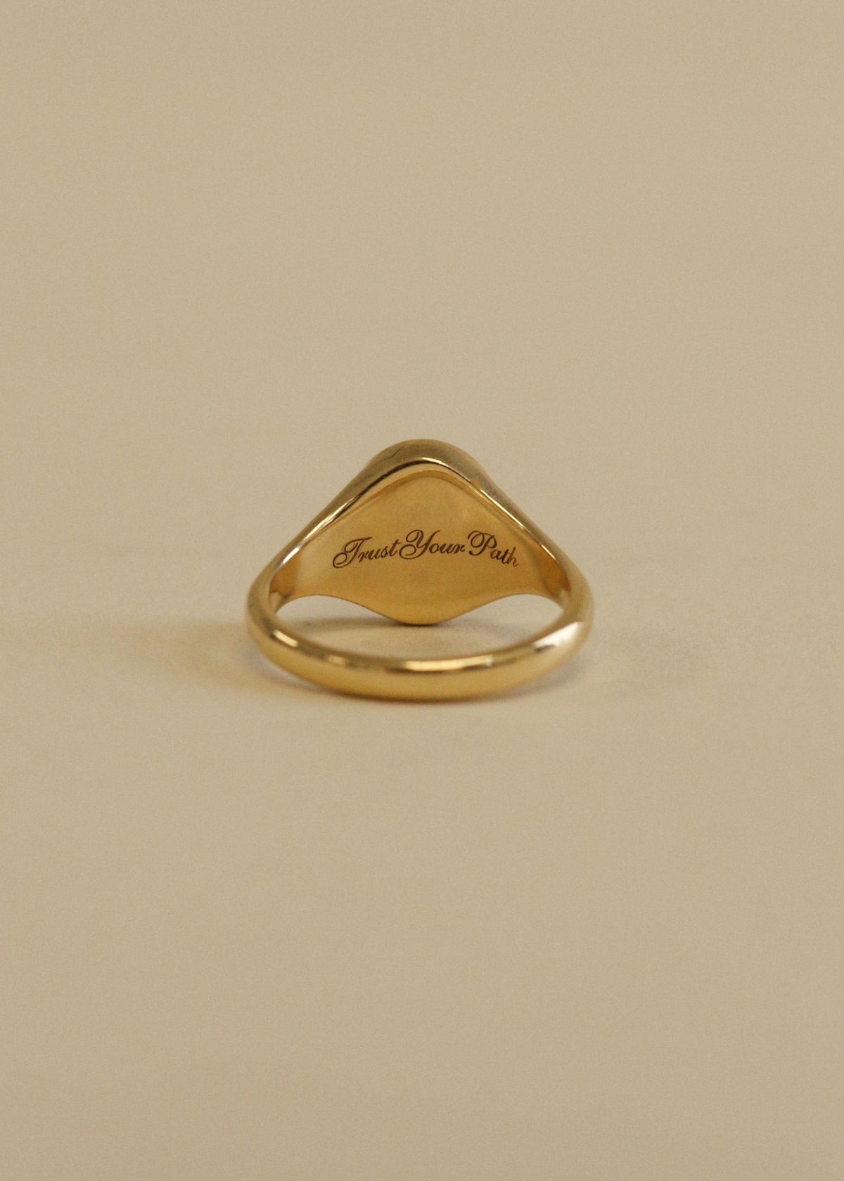 A Kinn 14k Gold Swan Dream Diamond Signet Ring showing "Trust Your Path"  engraved in script on the back of the signet