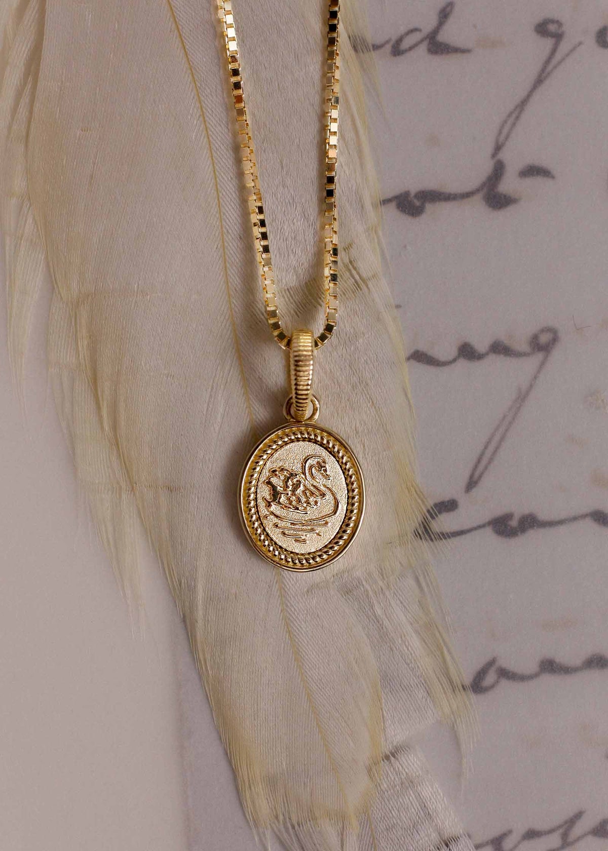 close up of a Kinn Studio 14k Gold Swan Dream Pendant on a box chain