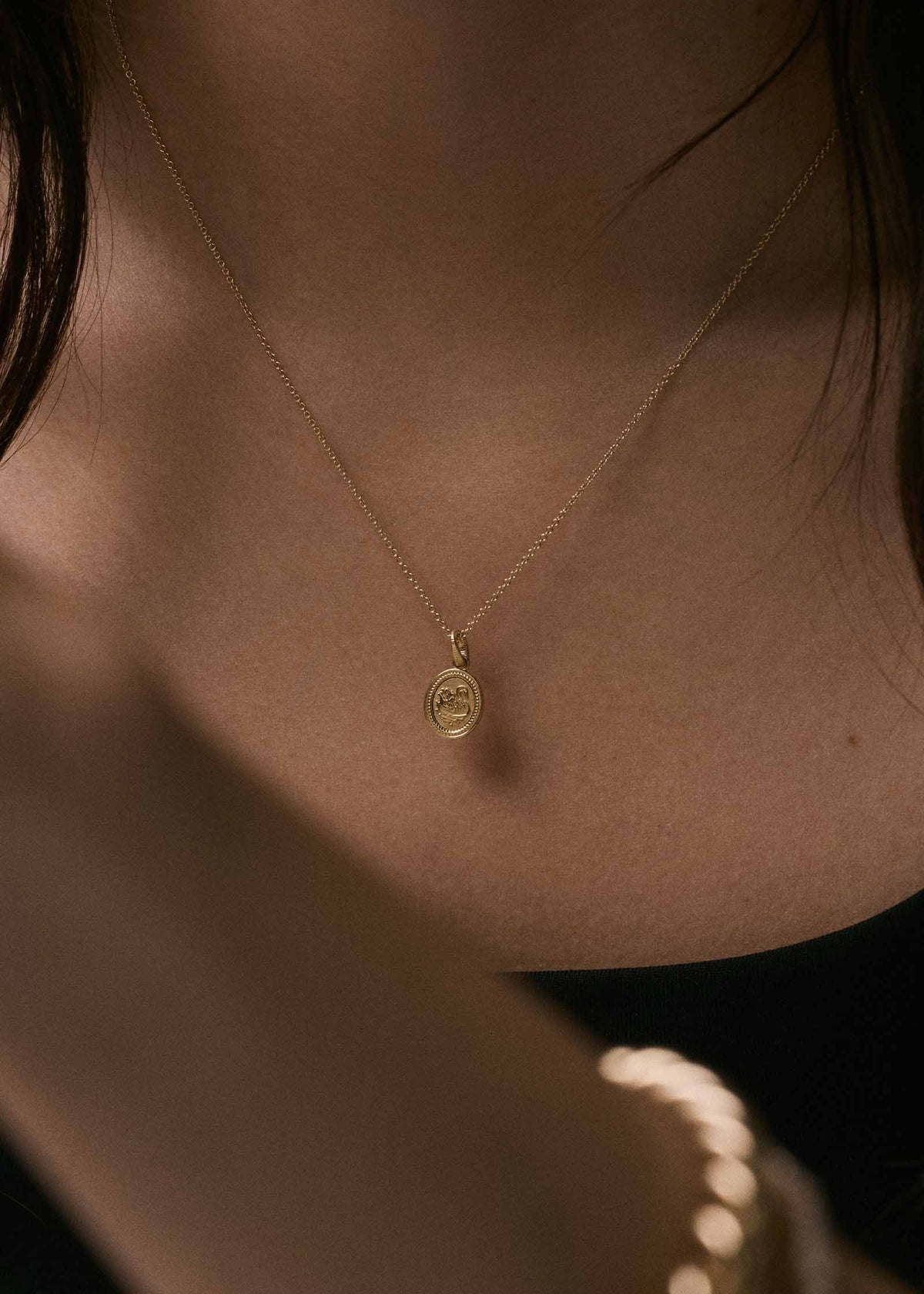 woman wearing a Kinn 14k Gold Swan Dream Pendant Necklace on Micro Rolo Chain