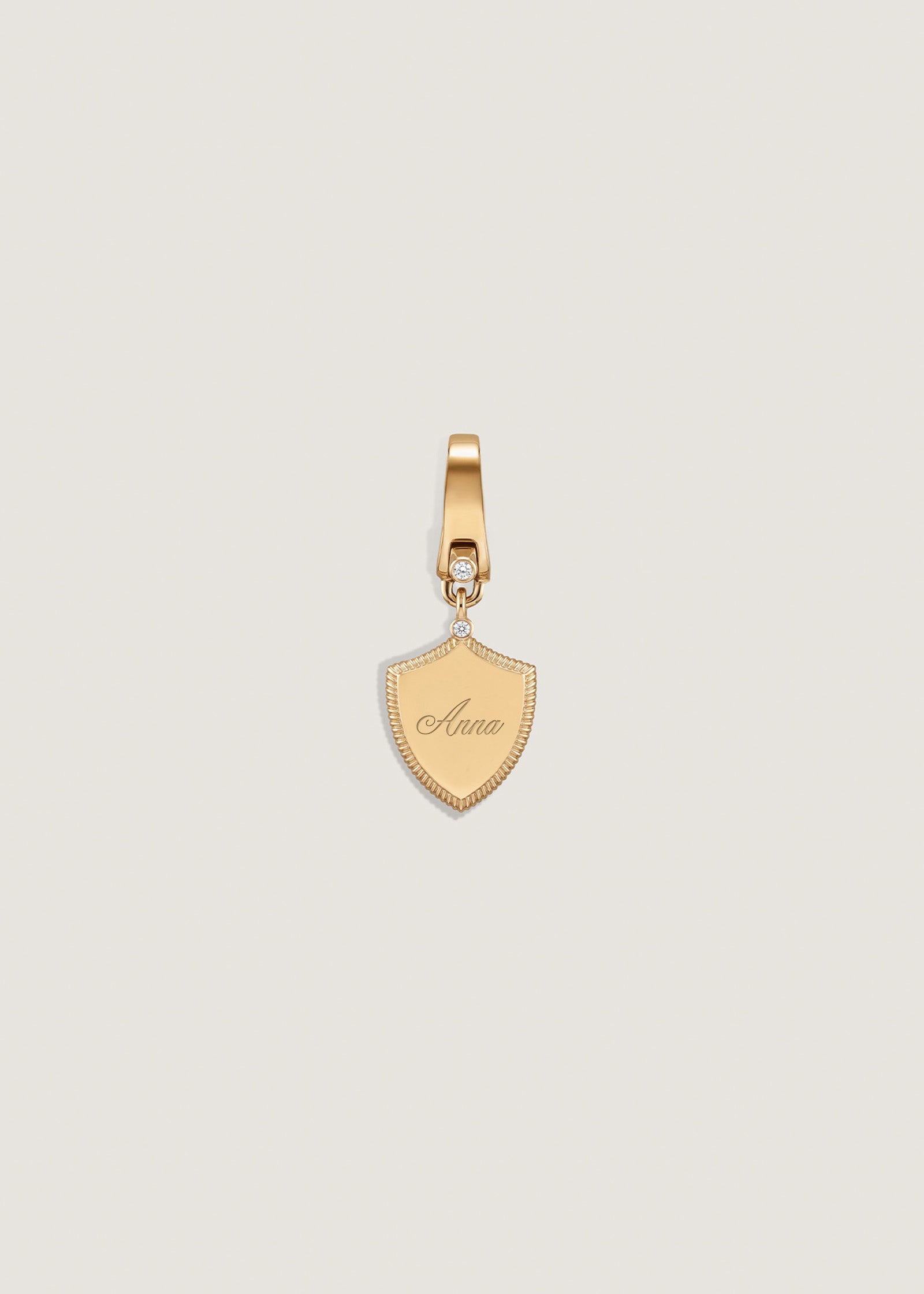 A Kinn 14k Gold Ace Shield Diamond Pendant engraved with the name "Anna" in york script font
