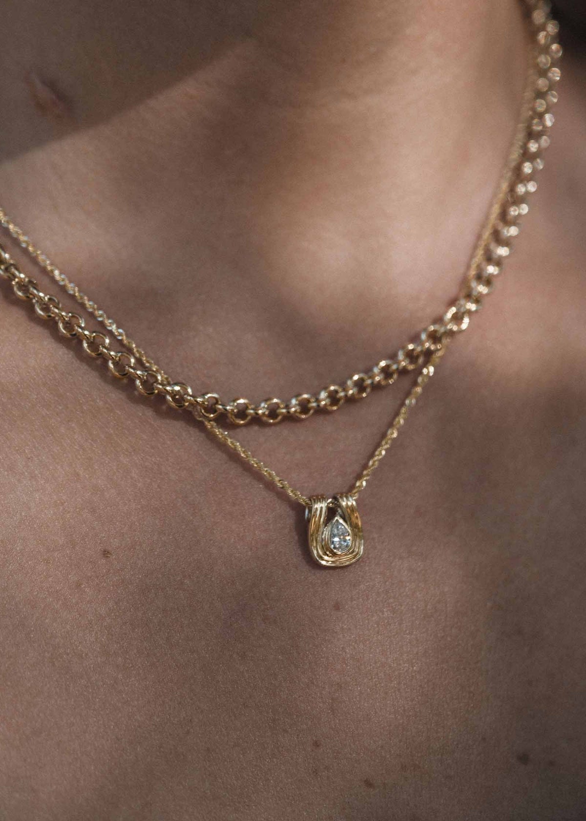 close up of a woman wearing a Kinn Studio 14k Gold Alyssa Pear Diamond Pendant on a Petite Rope Chain layered with a Matis Rolo Chain