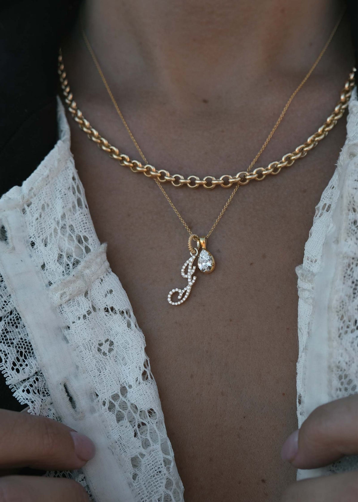 woman wearing a Kinn 14k Gold Clara Pear Diamond Pendant Necklace with a Pave Diamond Love Letter Pendant and layered with a Matis Rolo Chain Necklace