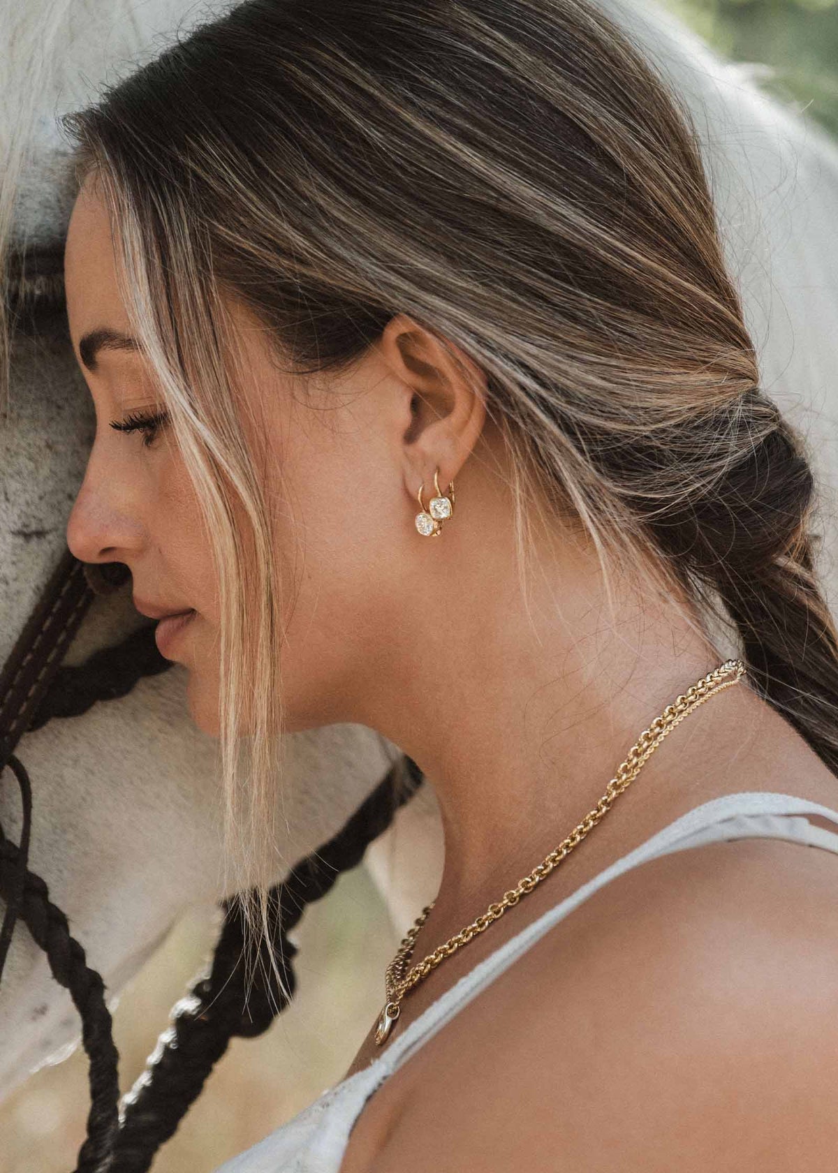 woman standing next to a horse wearing Kinn 14k Yellow Gold Harper 2ctw Round Drop Earrings