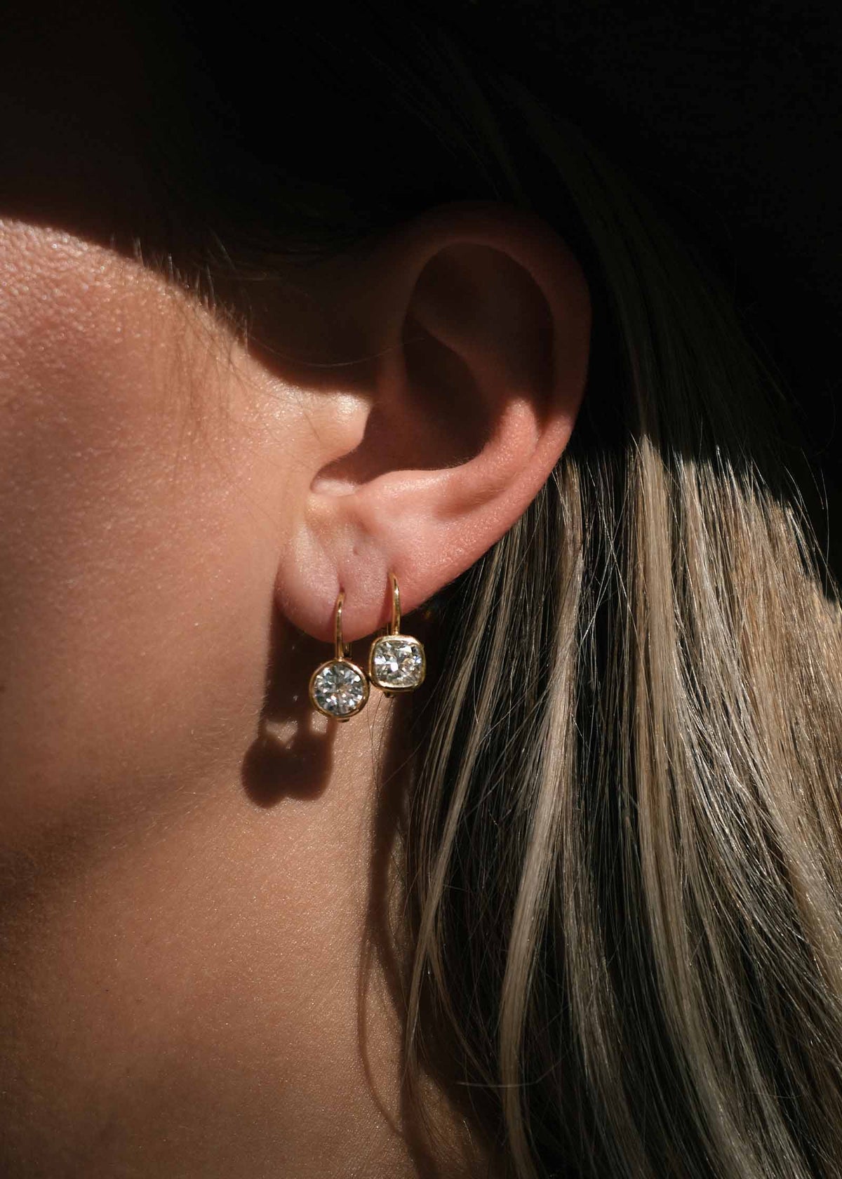 woman wearing Kinn 14k Yellow Gold Harper 2ctw Round Drop Earrings layered with 14k Gold Harper Cushion Drop Earrings