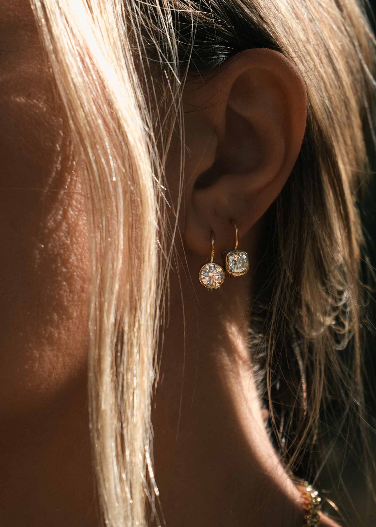 woman wearing Kinn 14k Yellow Gold Harper 2ctw Round Drop Earrings layered with 14k Gold Harper Cushion Drop Earrings