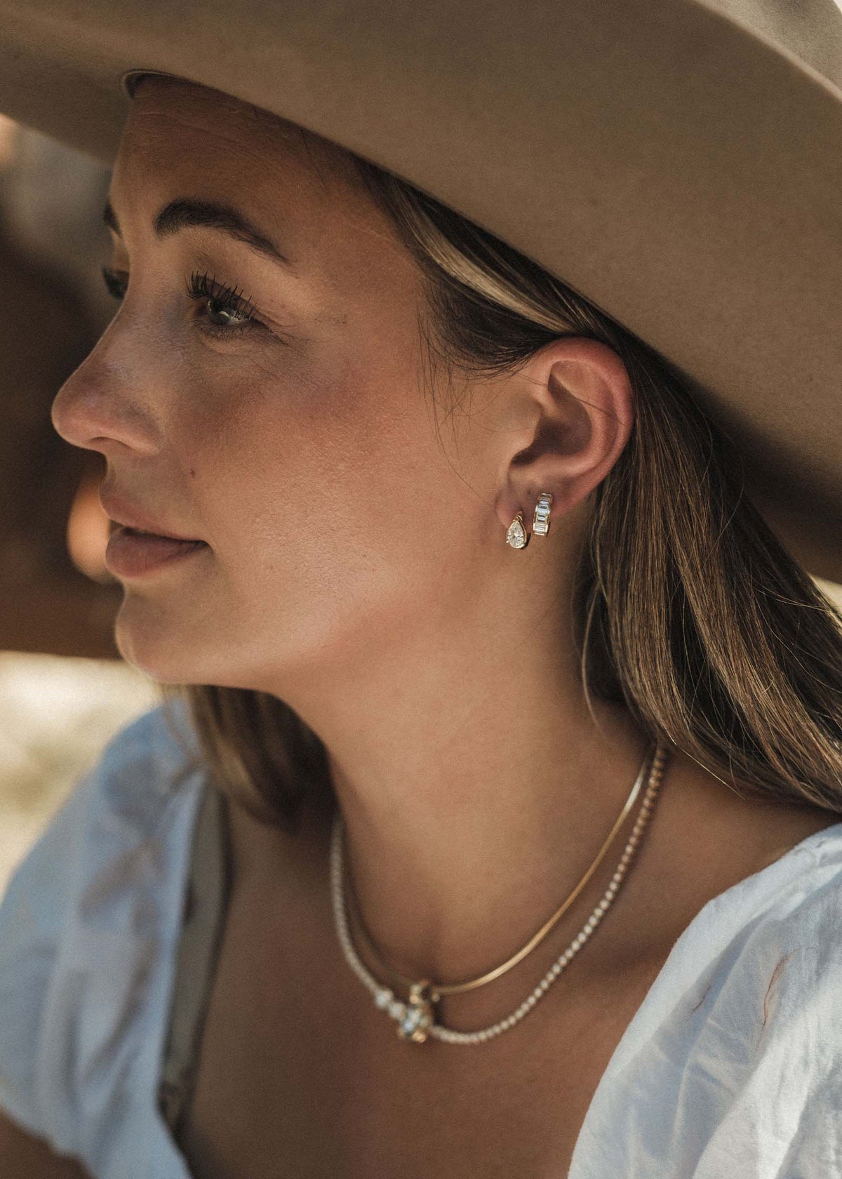 woman wearing Kinn 14k Gold Jackson Pear Diamond Huggie Hoop Earrings