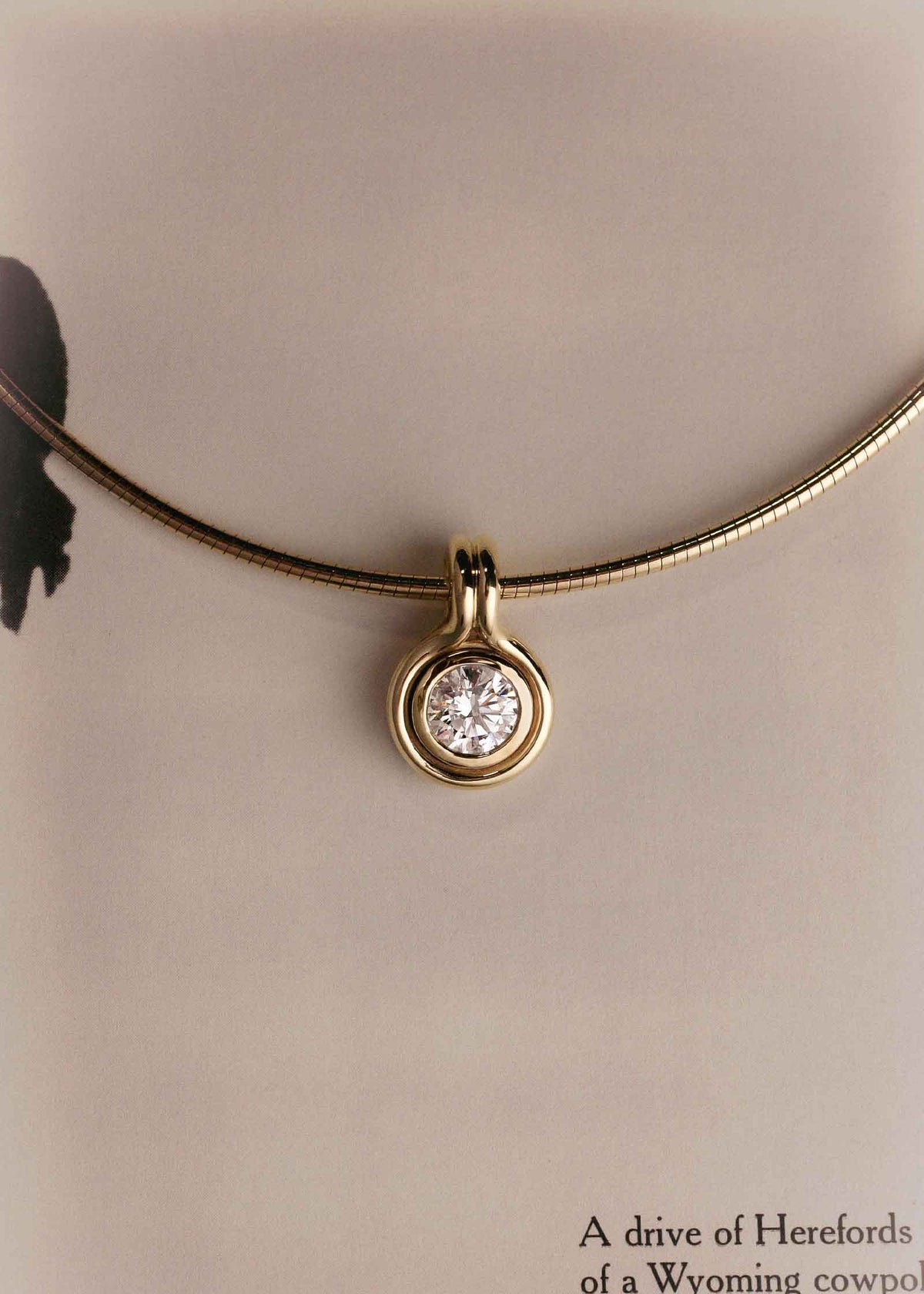 A Kinn Studio 14k Gold Jody Round Diamond Pendant on an Heirloom Curved Chain laying flat