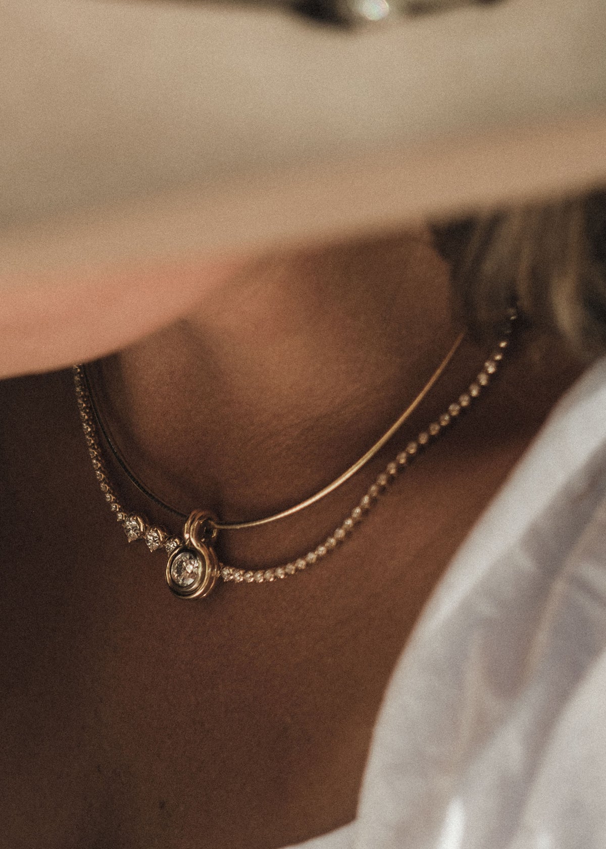 A close-up lifestyle shot of a person wearing a Kinn Studio 14k Gold Jody Round Diamond Pendant on an Heirloom Curved Chain Necklace