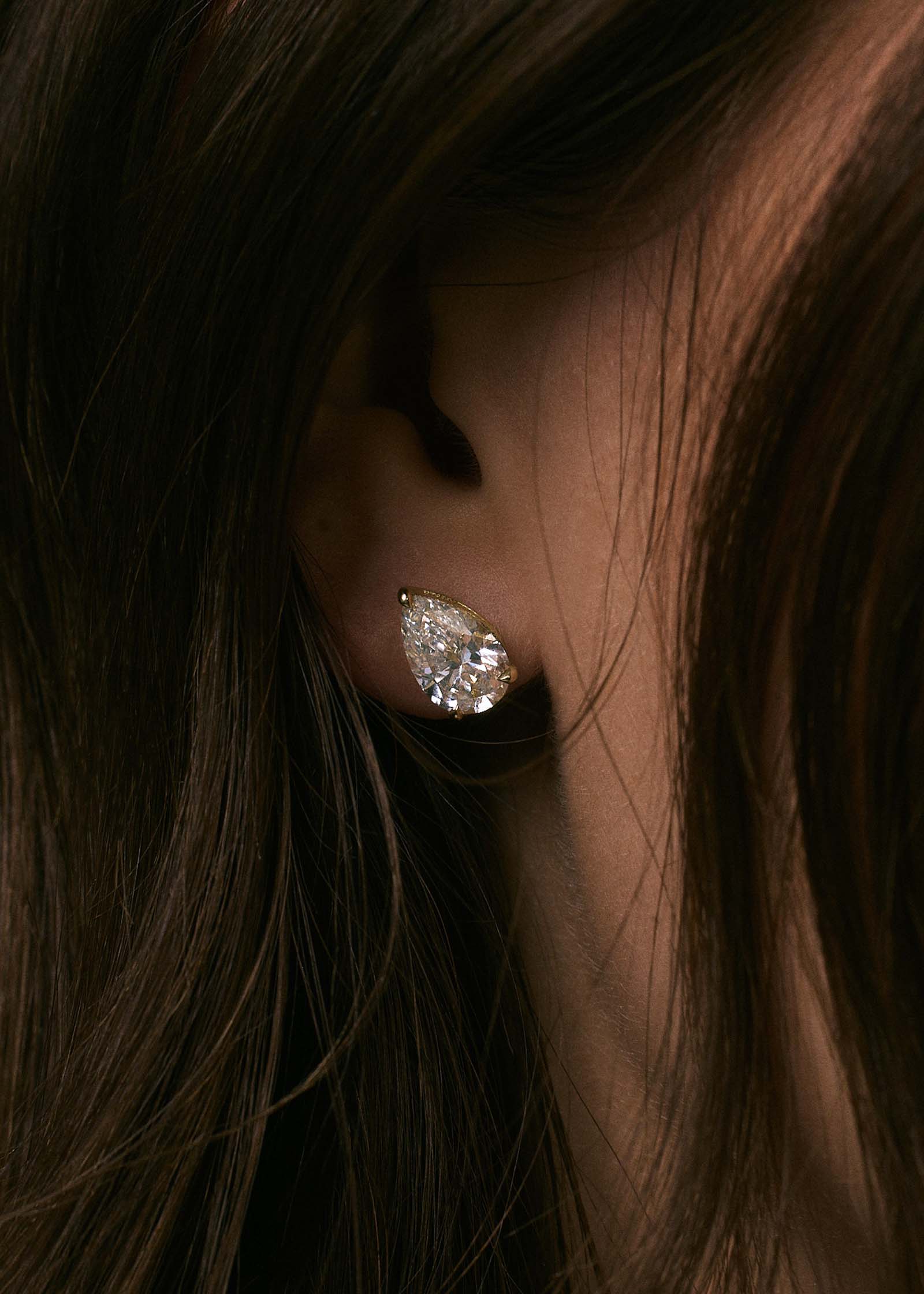 close up of a woman's ear wearing a Kinn x Prince 14k Gold June Pear Diamond Stud Earring