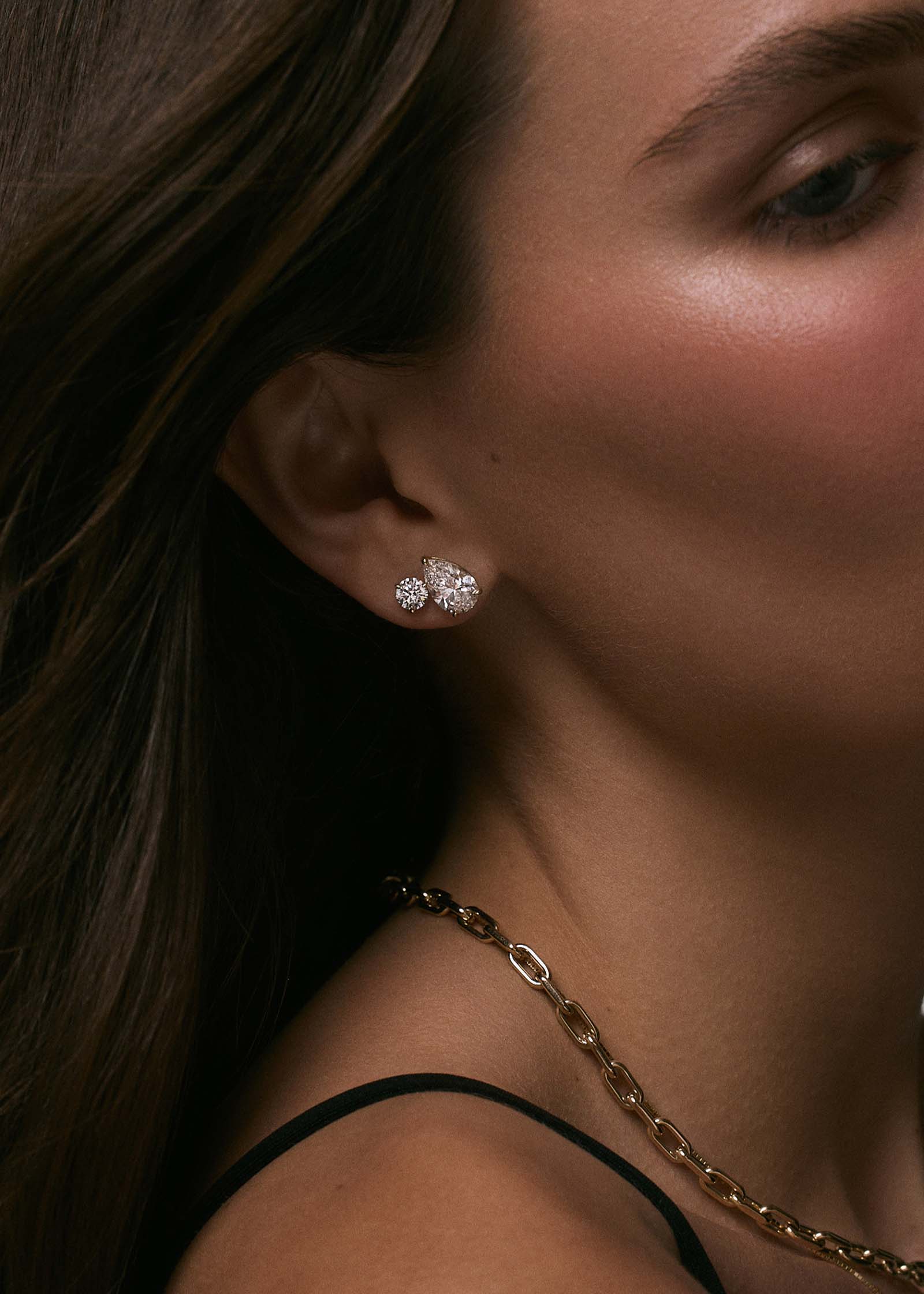 A woman wearing Kinn x Prince 14k Gold June Pear Diamond Stud Earrings and a June Round Diamond Stud in her second piercing
