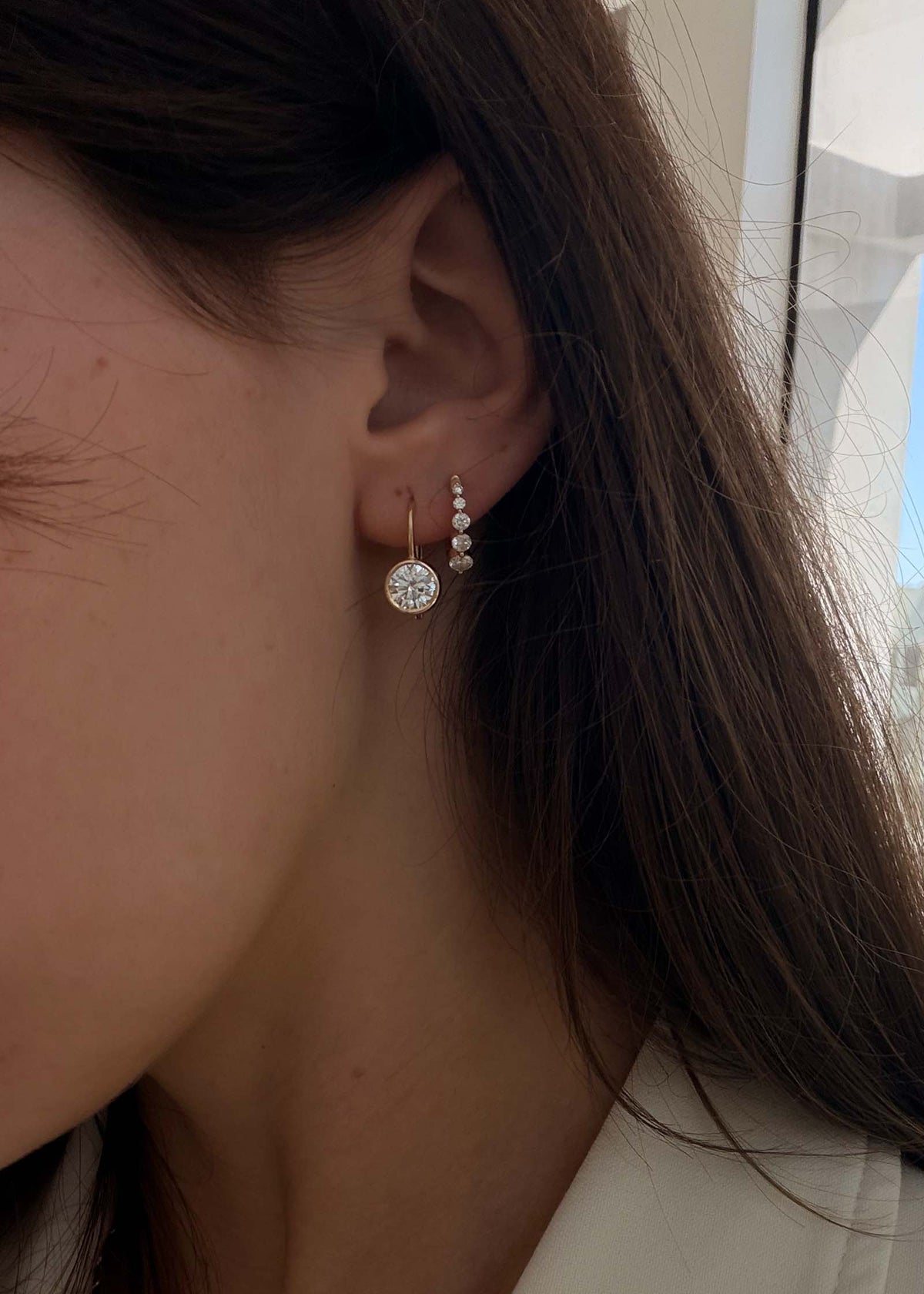 A woman wearing a Harper Round Drop Earring with a Graduated Diamond Huggie Earring